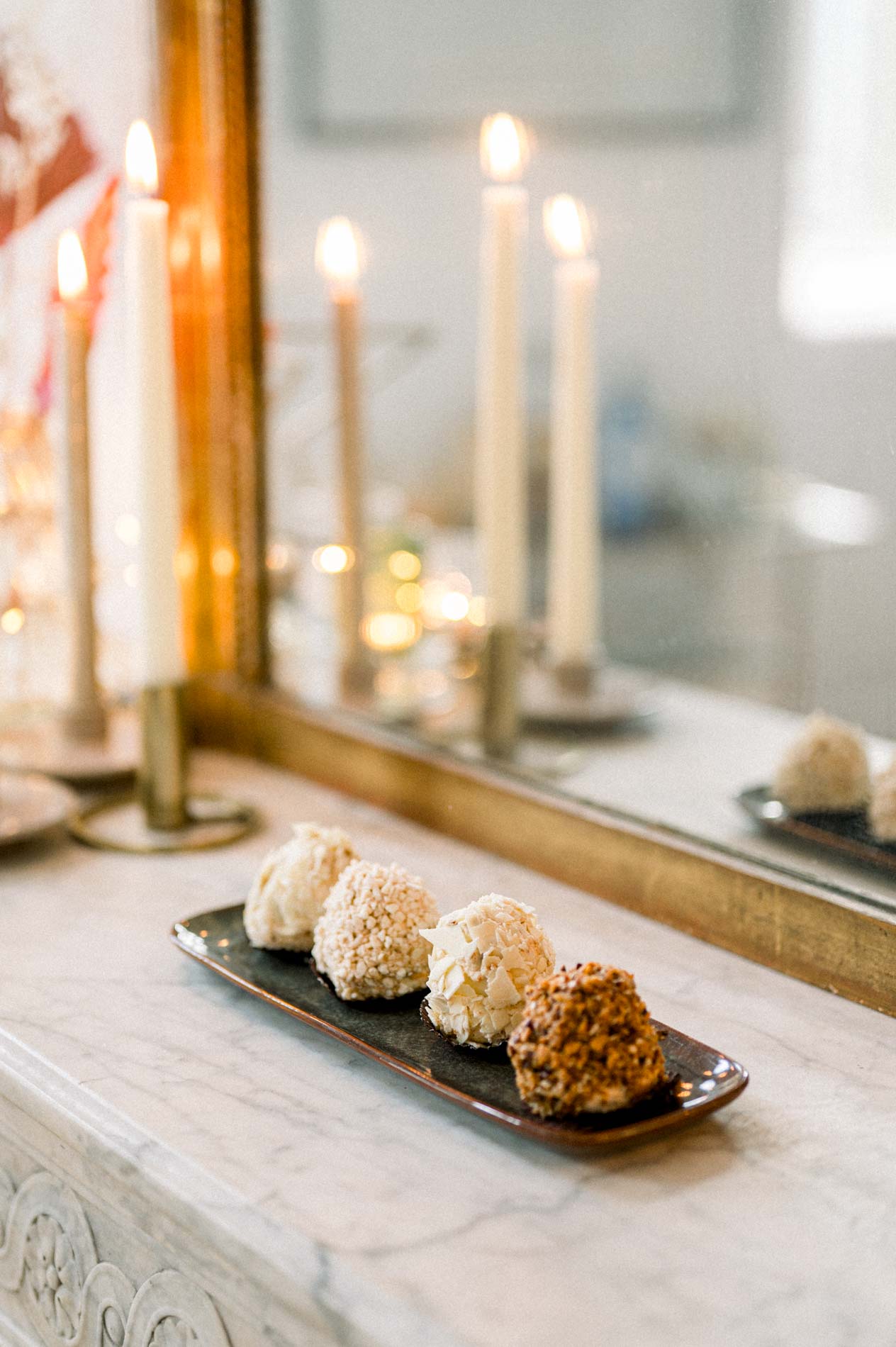 Candles and small cakes on the marble mantelpiece before a mirror