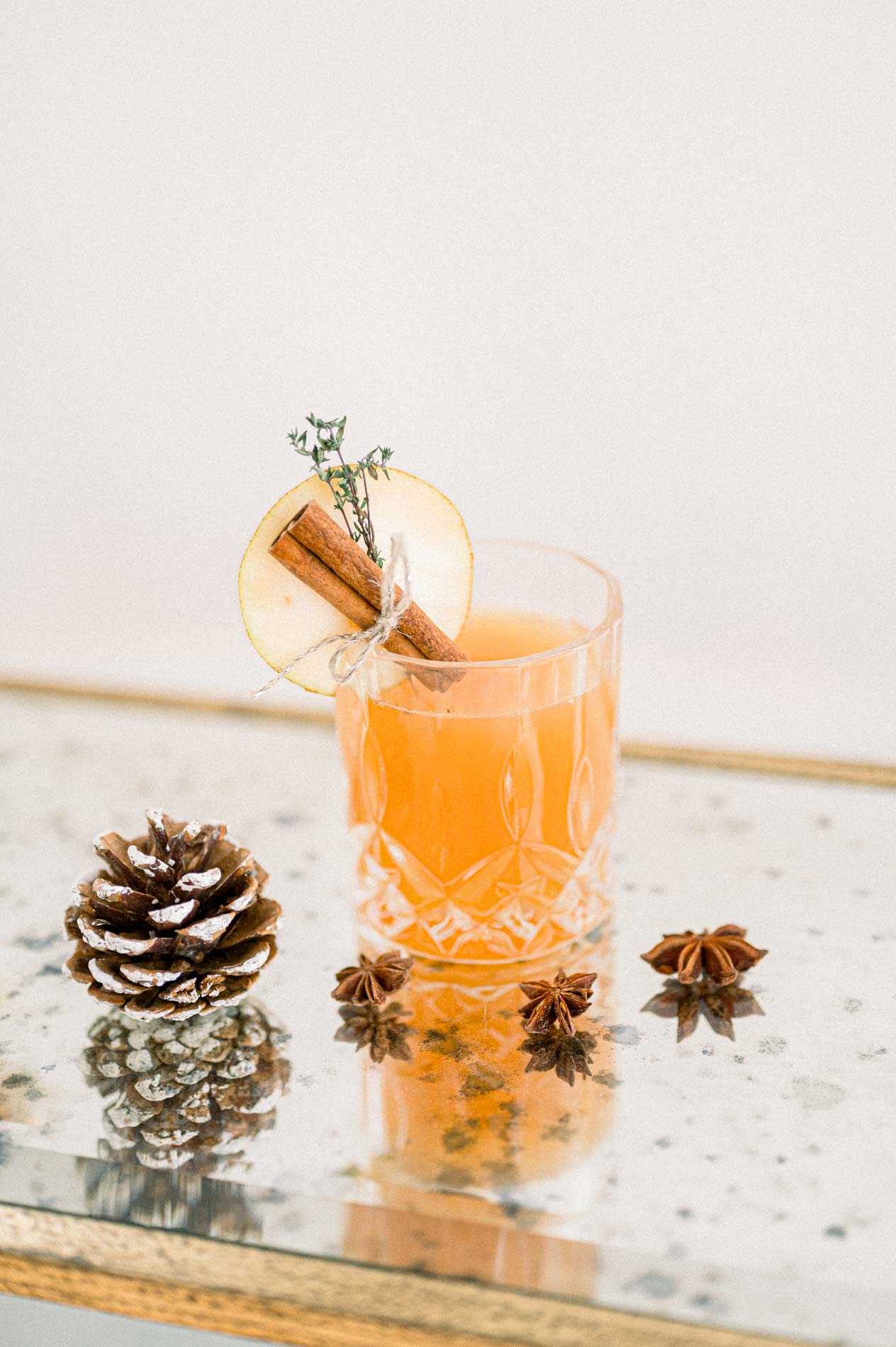 Christmas cocktail with cinnamon, a pine cone and star anise