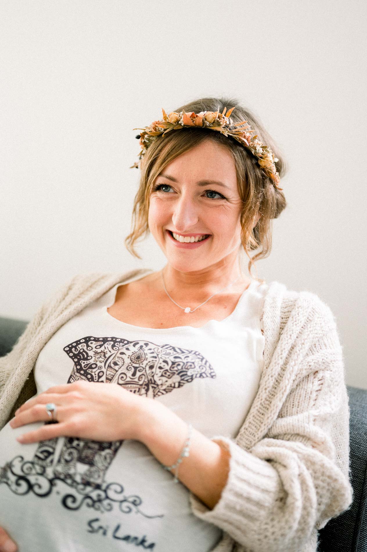 Portrait souriant de la future maman en gilet crème et couronne de fleurs