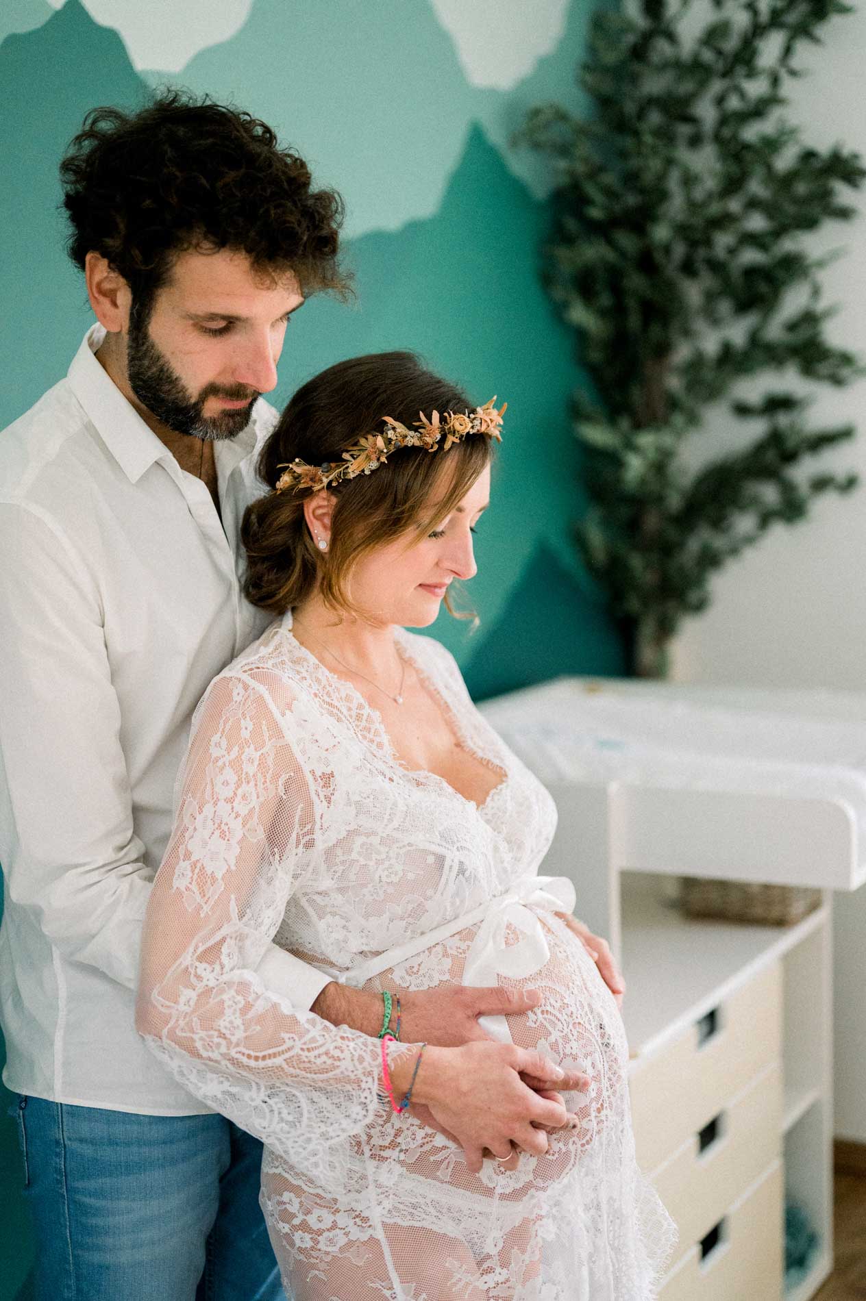 Futurs parents enlacés près de la commode de la chambre de bébé