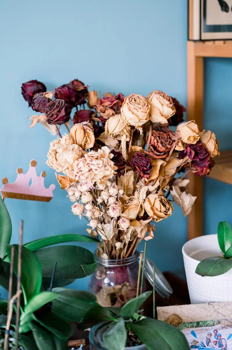 Bouquet of dried roses and candles on a cabinet against a blue wall