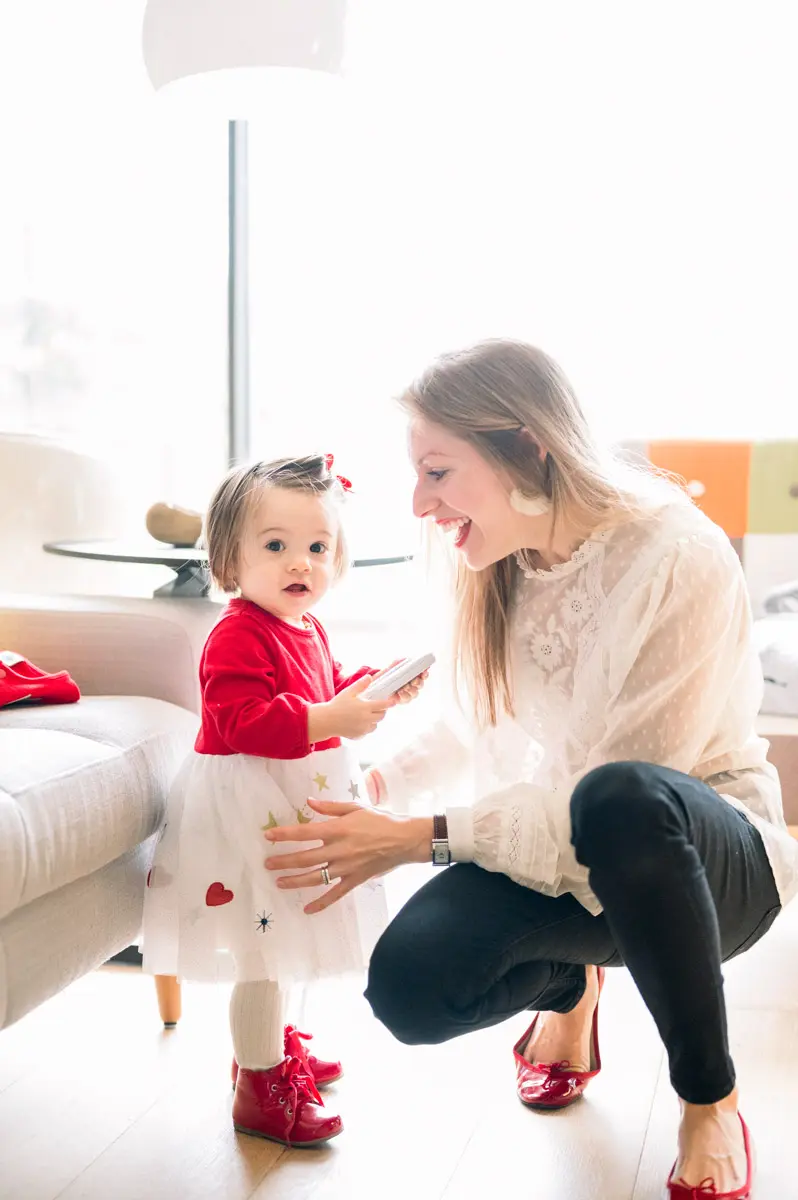 Mother crouching facing her daughter as she toddles across the living room