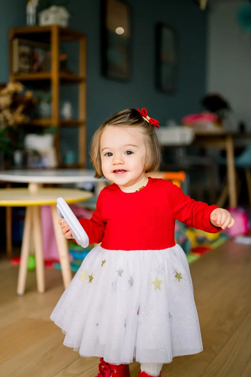 Little girl in a starry tulle skirt walking across the living room