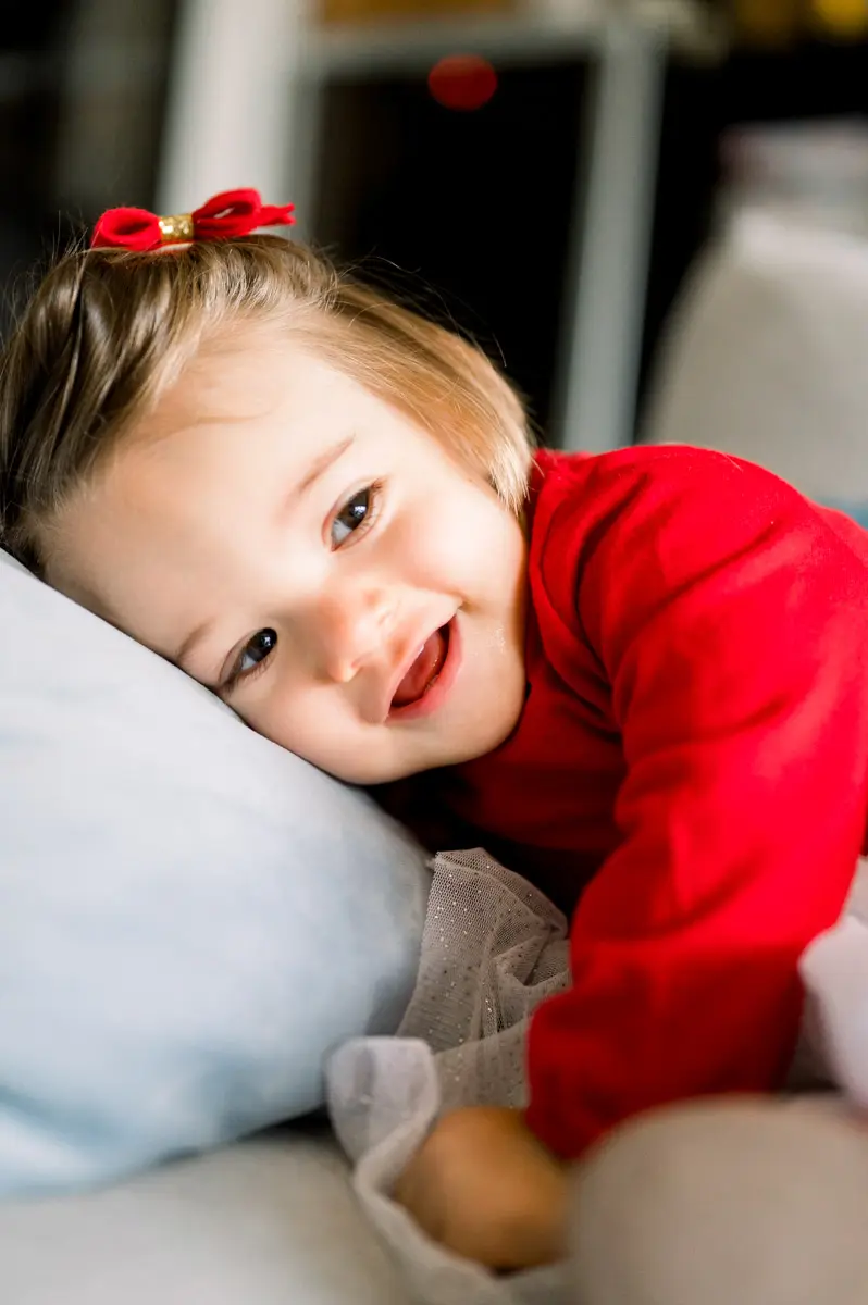 Mischievous little girl lying against a cushion, red clip in her hair