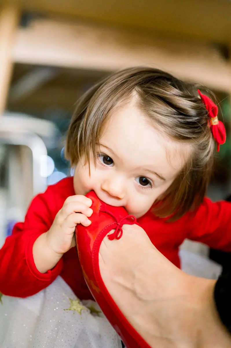 Little girl nibbling her red shoe with a cheeky look