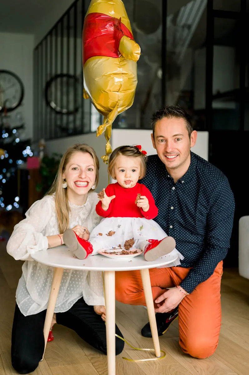 Parents with their little girl sitting on the table after the birthday cake