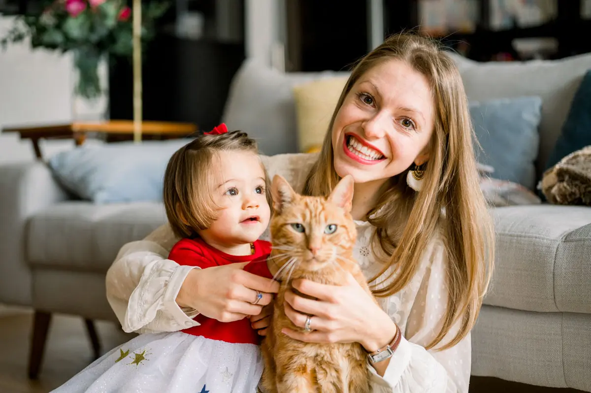Smiling mother and daughter sitting on the floor with the ginger cat