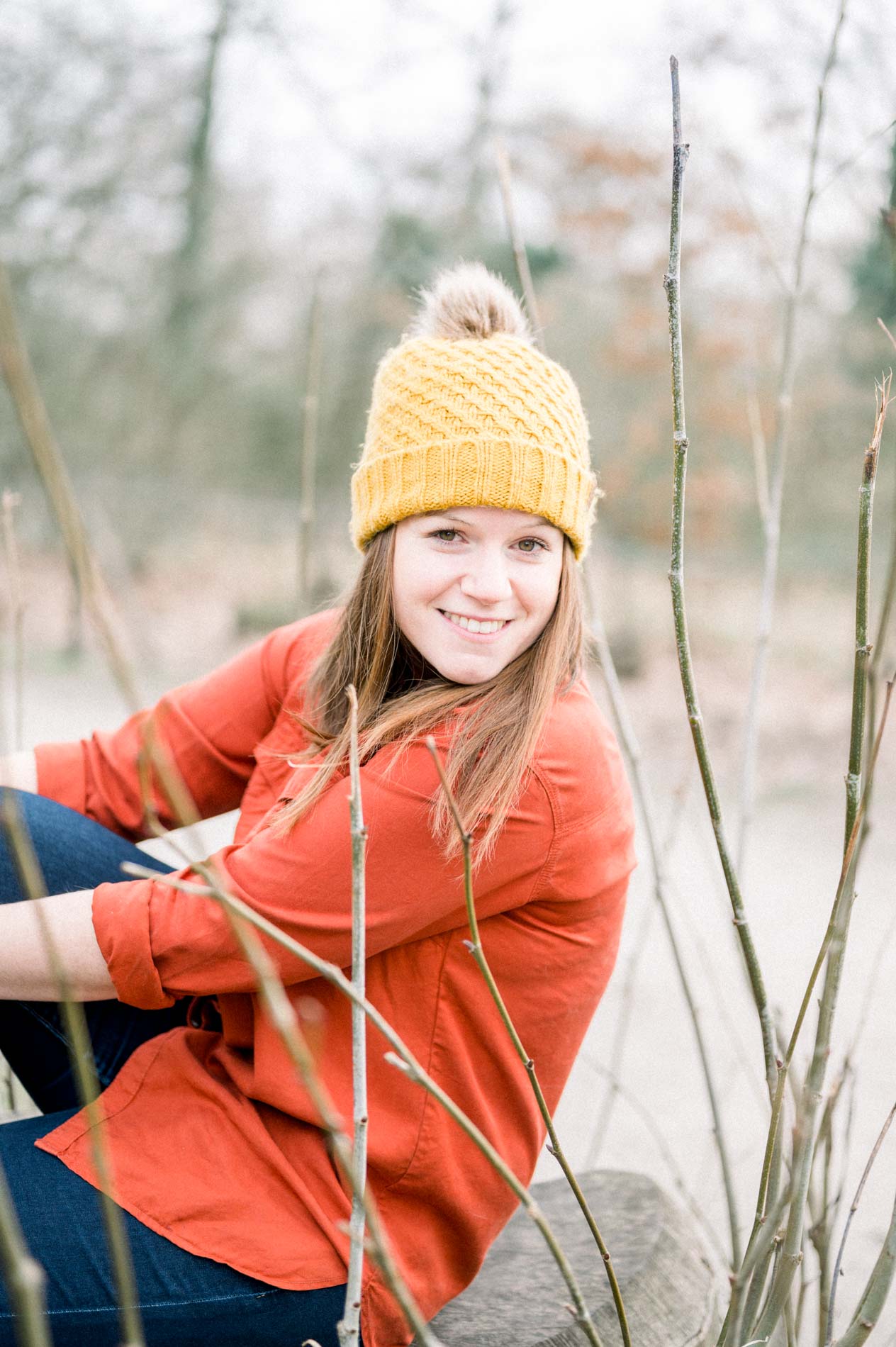 Young woman in a mustard beanie and orange shirt sitting in the Parc Bordelais
