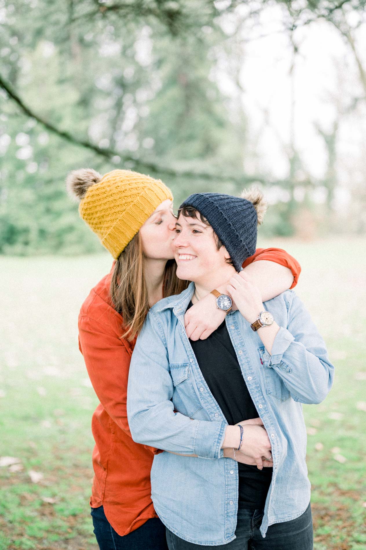 She hugs her partner from behind and kisses her cheek