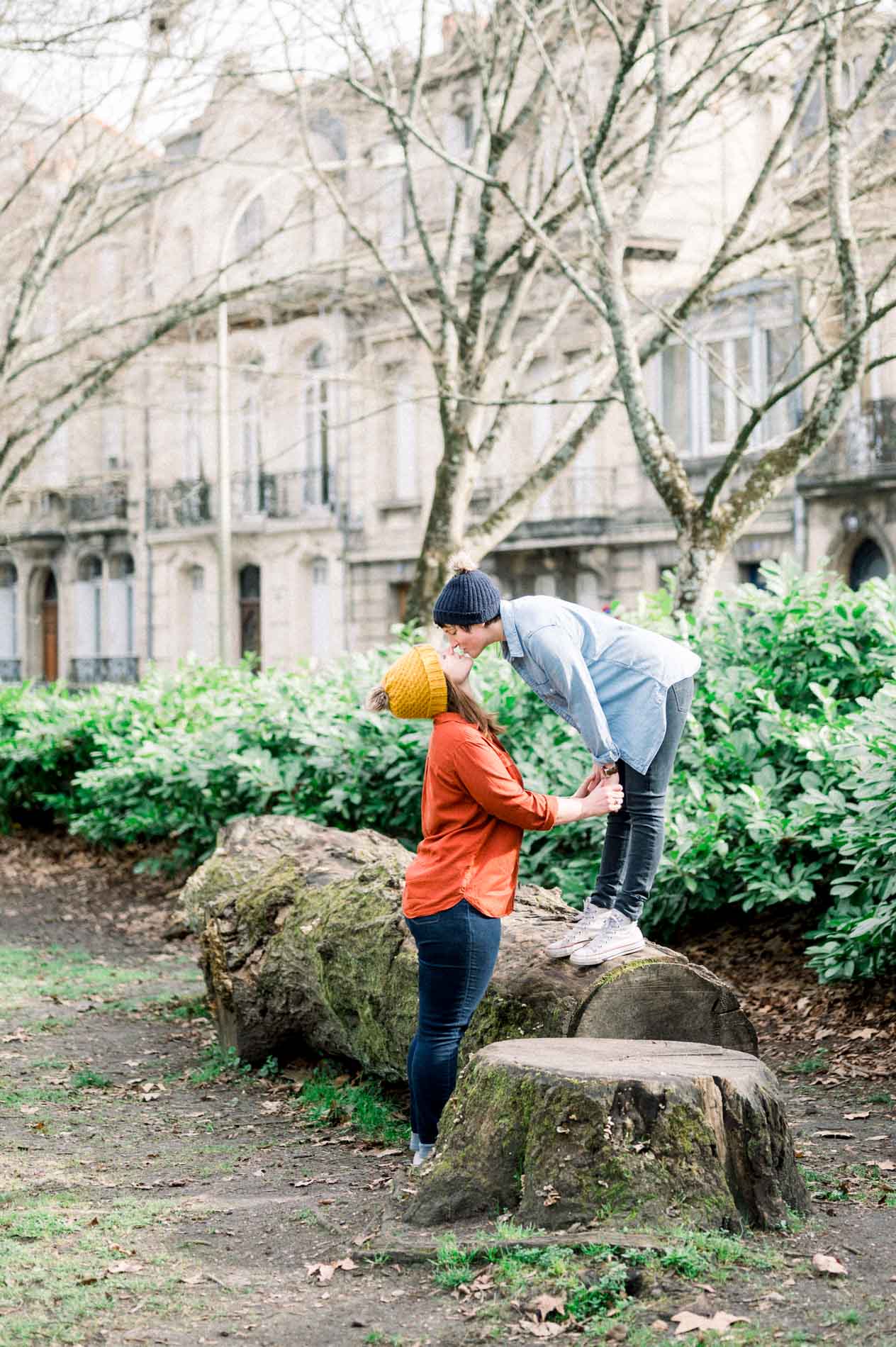 The couple playing on tree stumps before Bordeaux's stone facades
