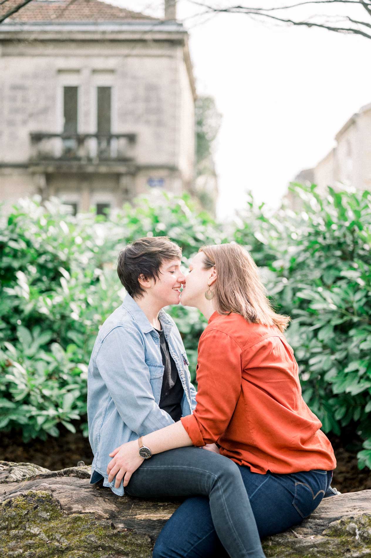 The couple kissing on a rock before a Bordeaux stone house