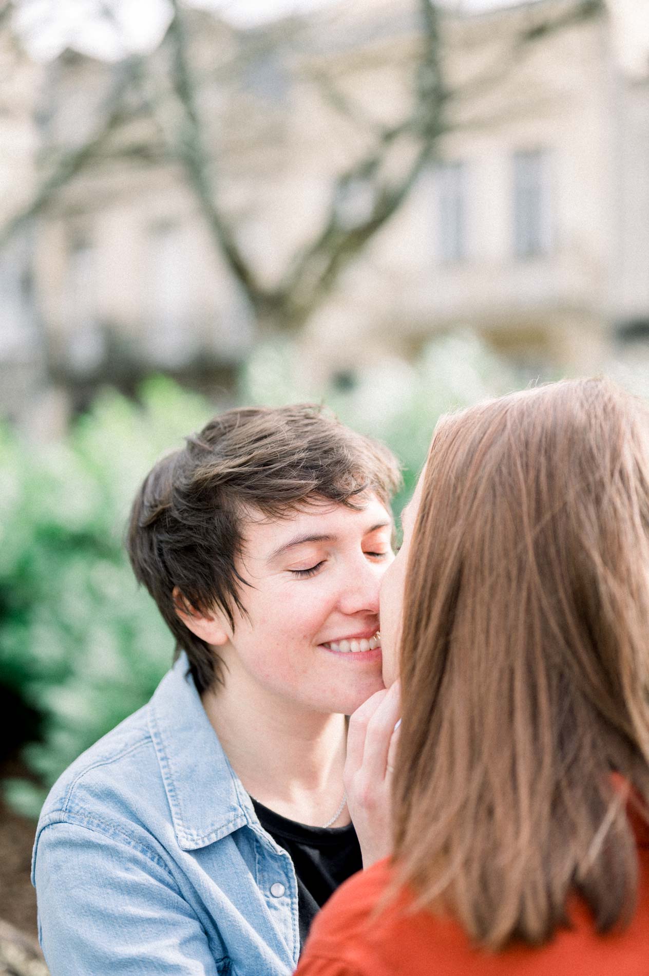 A woman smiling with eyes closed, forehead against her partner's