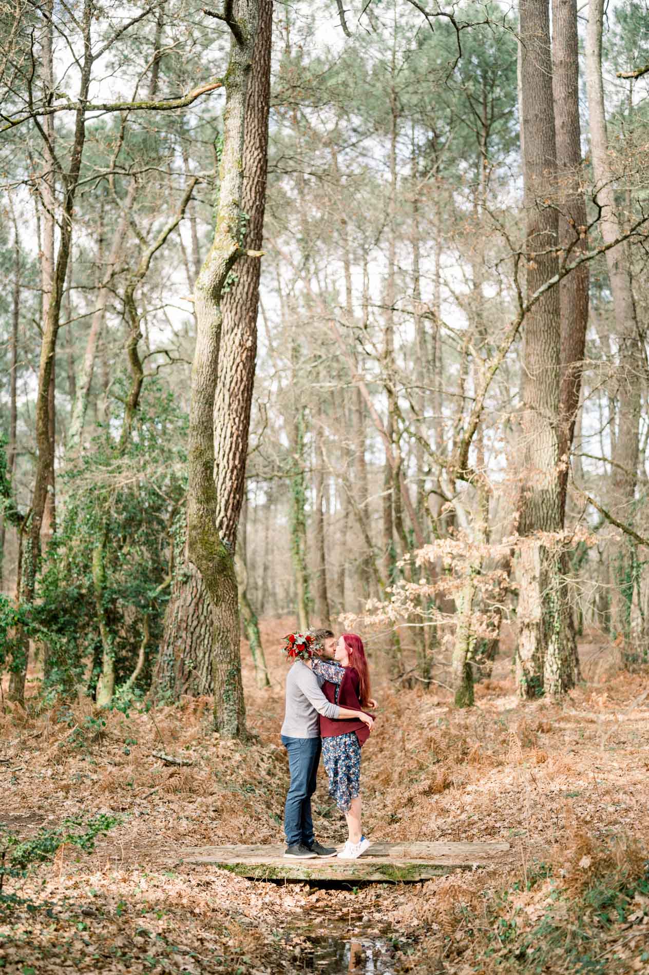 Couple embracing while standing on a stump in the pine forest