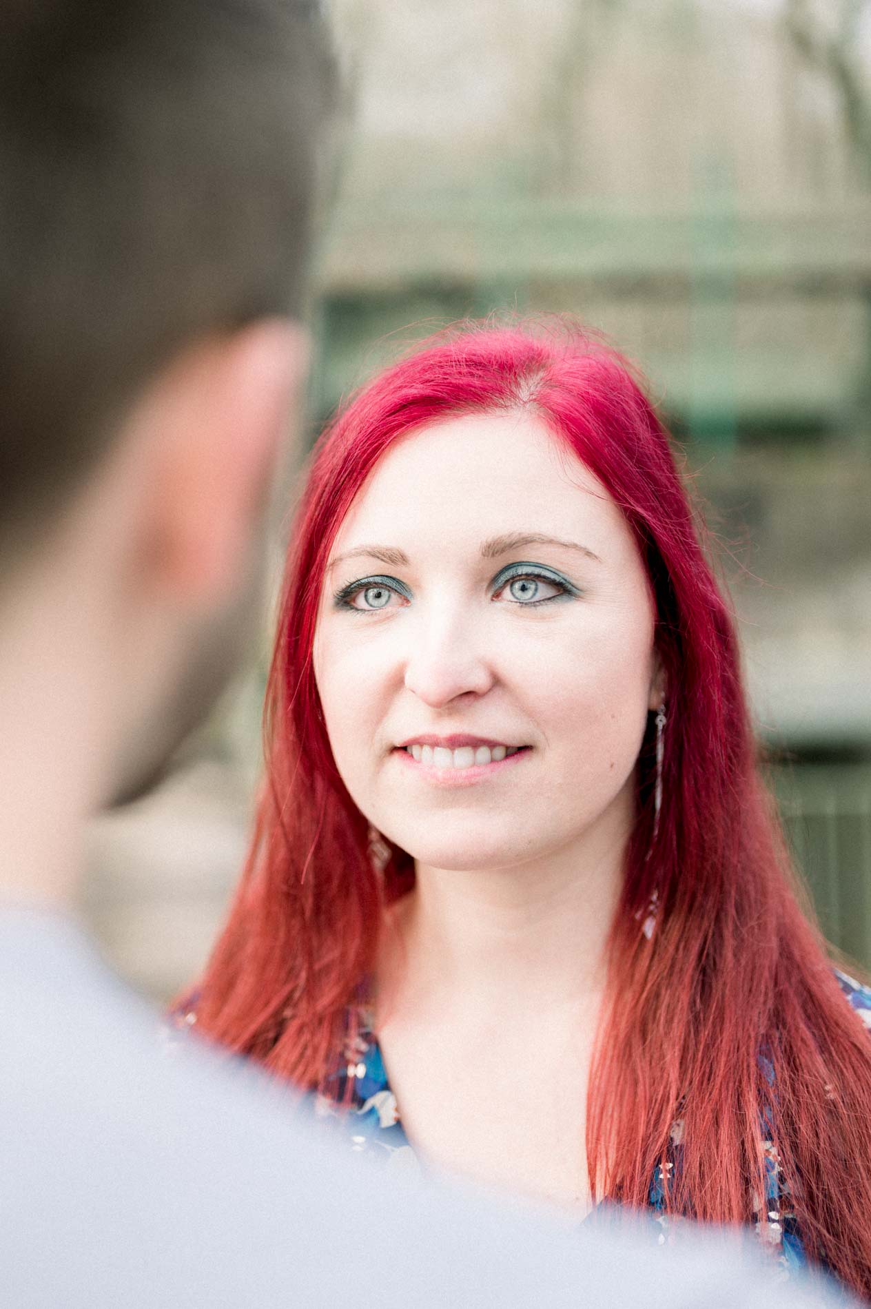 Light-eyed woman gazing into the distance, her partner in the foreground
