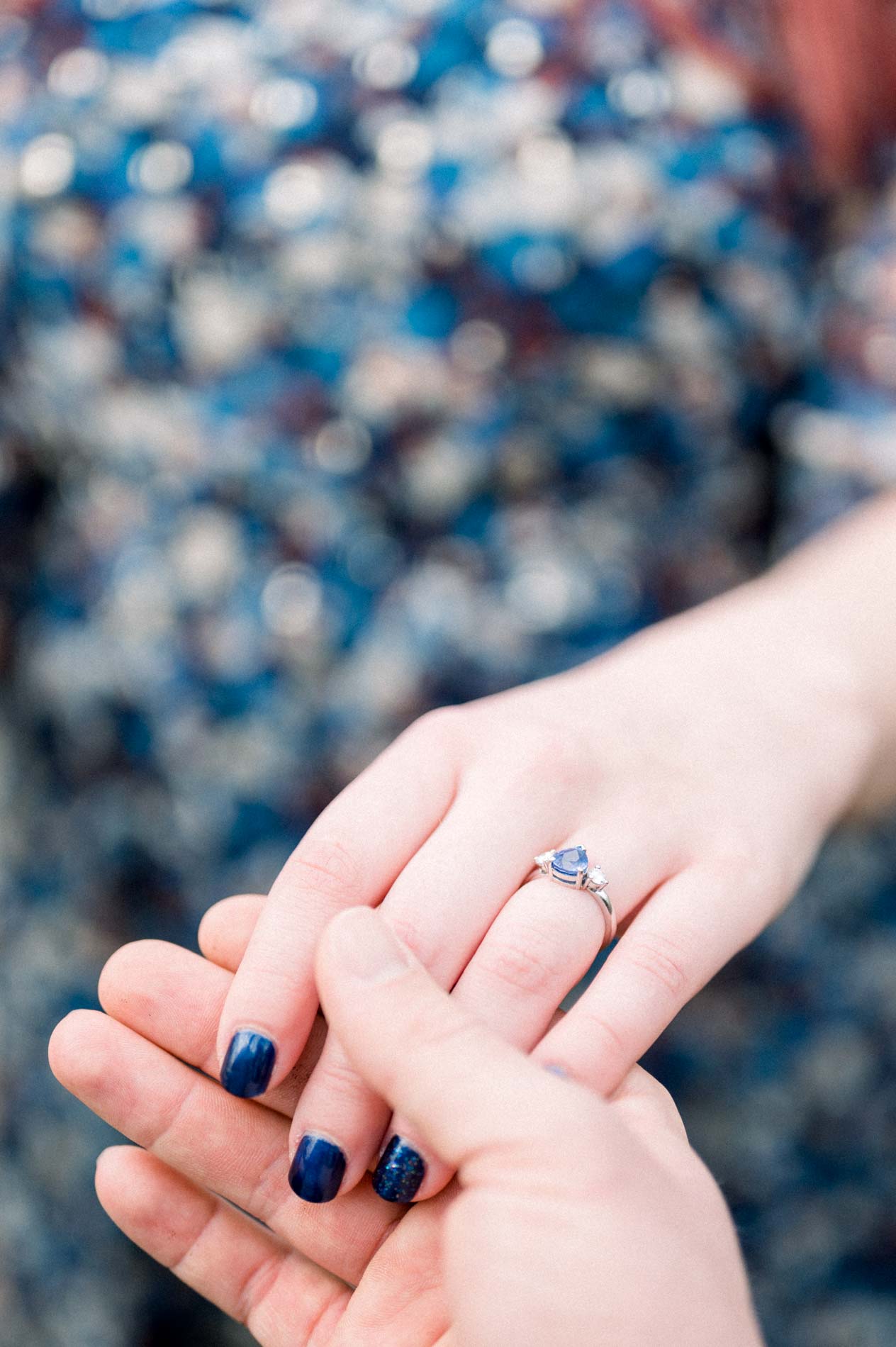 Close-up of the engagement ring as he holds her hand