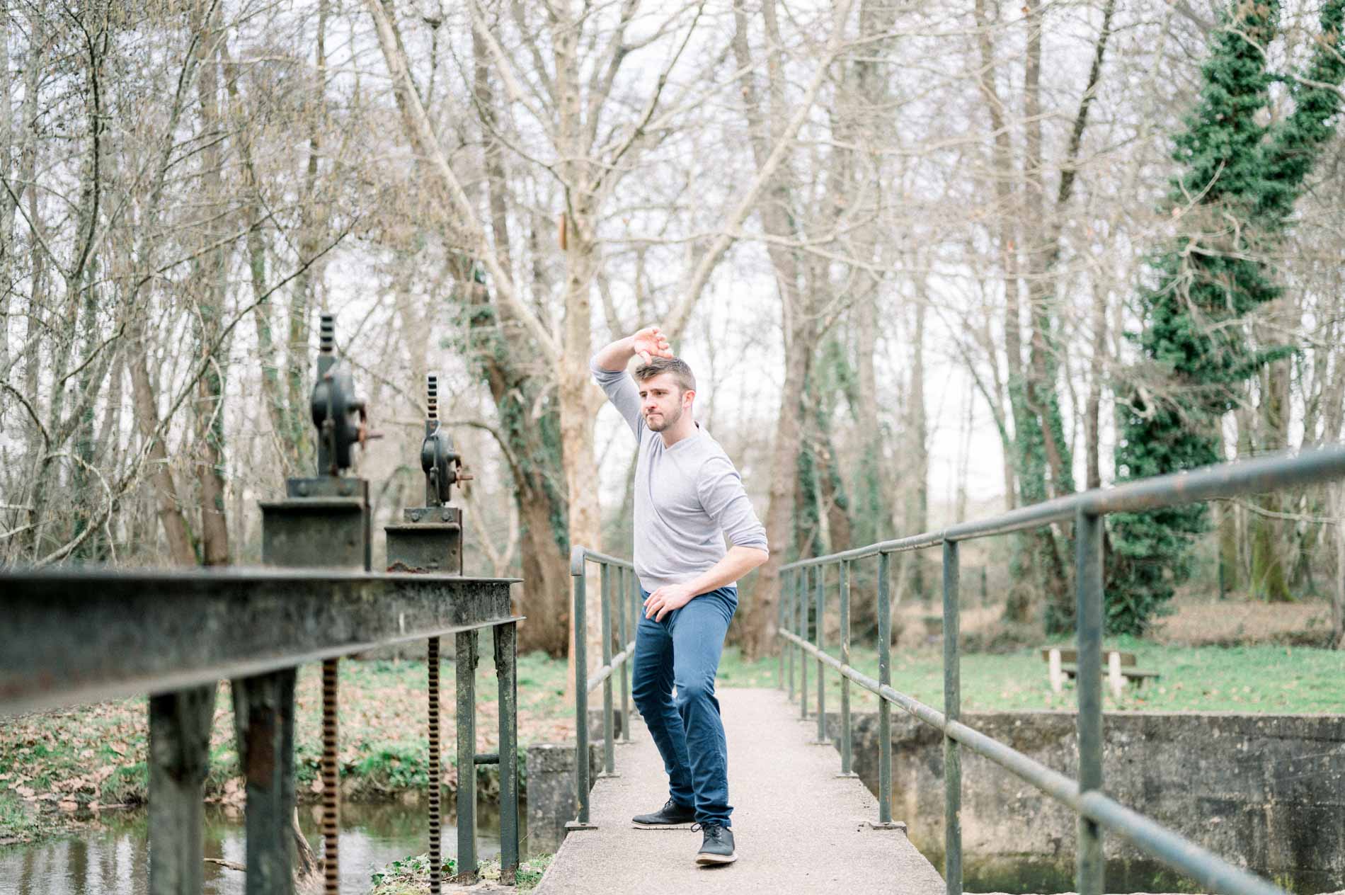 Man in a chanbara stance on a metal footbridge in the woods