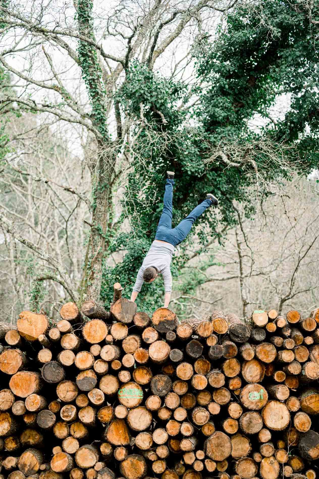 Man doing a handstand on top of the log pile