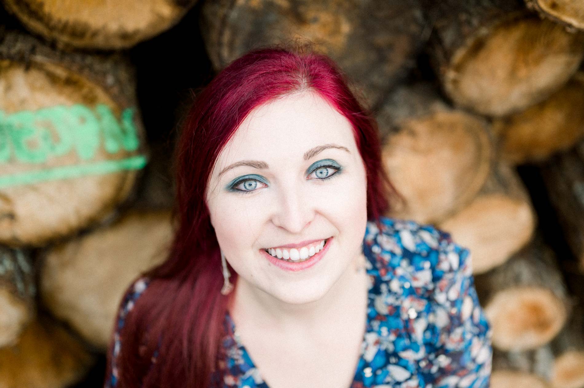 Smiling portrait of a red-haired woman in front of logs