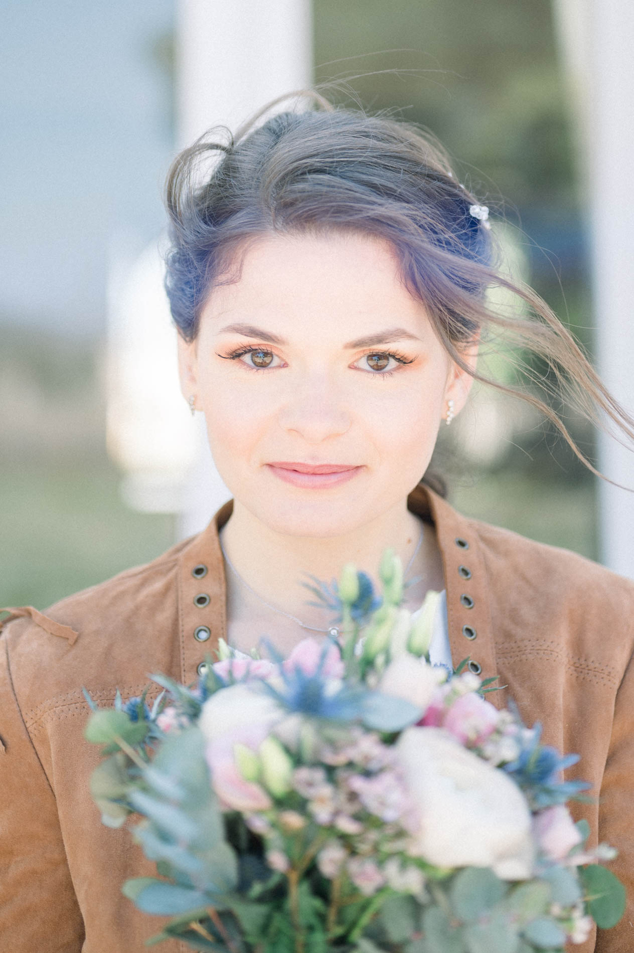 Portrait de la mariée en veste daim, cheveux au vent, bouquet à la main