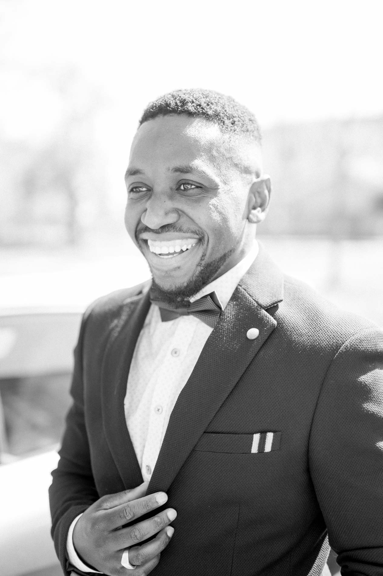 Portrait en noir et blanc du marié souriant en smoking et nœud papillon
