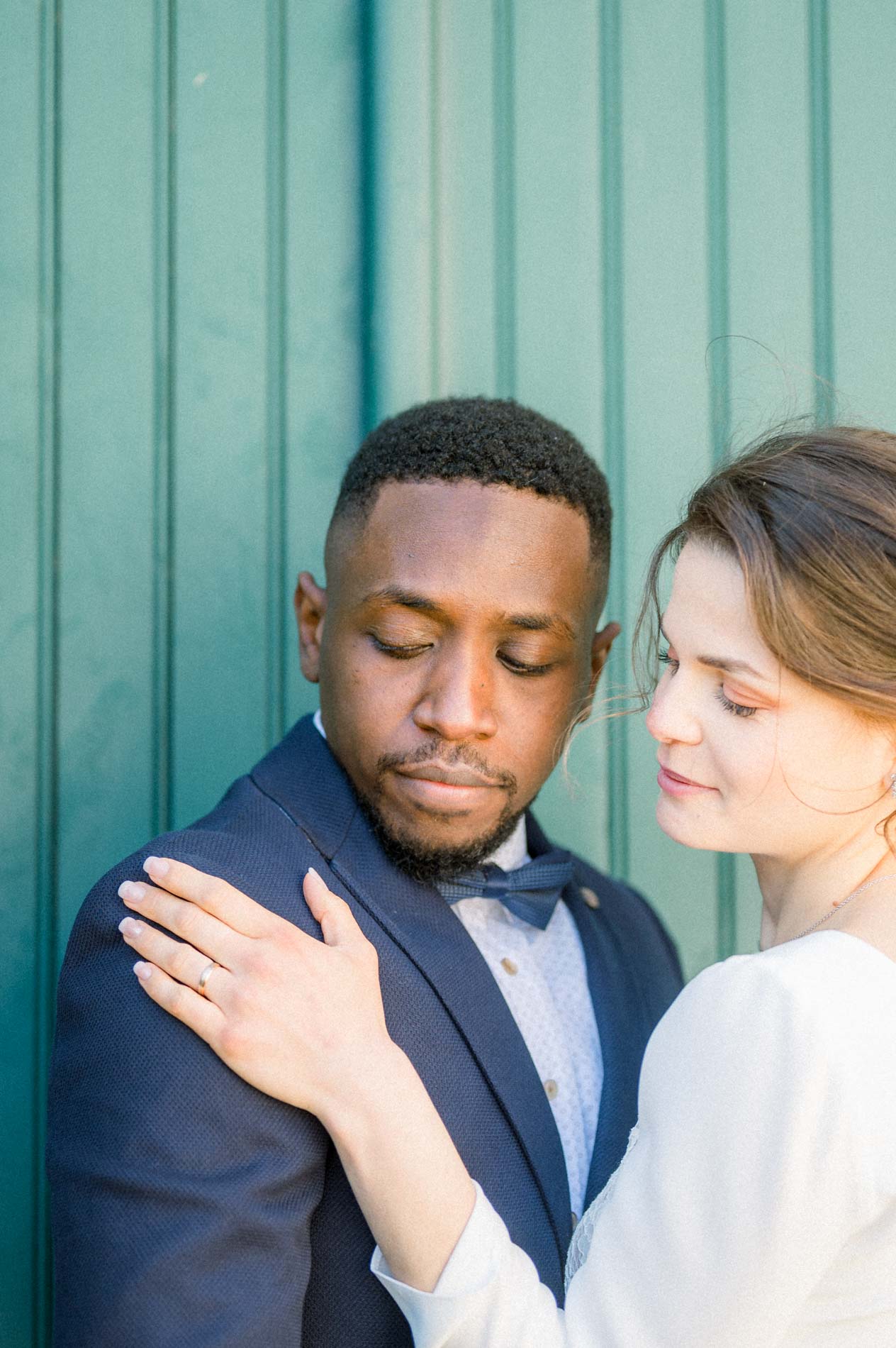 La mariée pose la main sur l'épaule du marié devant une porte verte