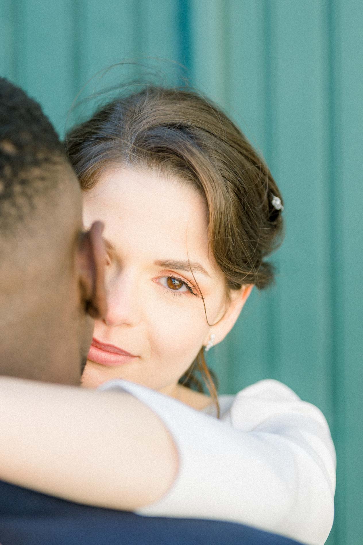 Le regard de la mariée par-dessus l'épaule du marié qu'elle enlace