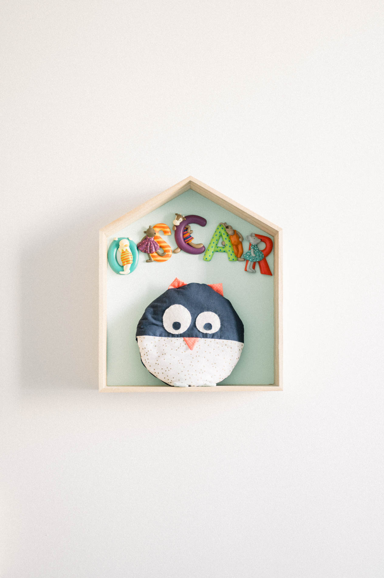 Étagère en forme de maison avec prénom en lettres colorées et peluche pingouin
