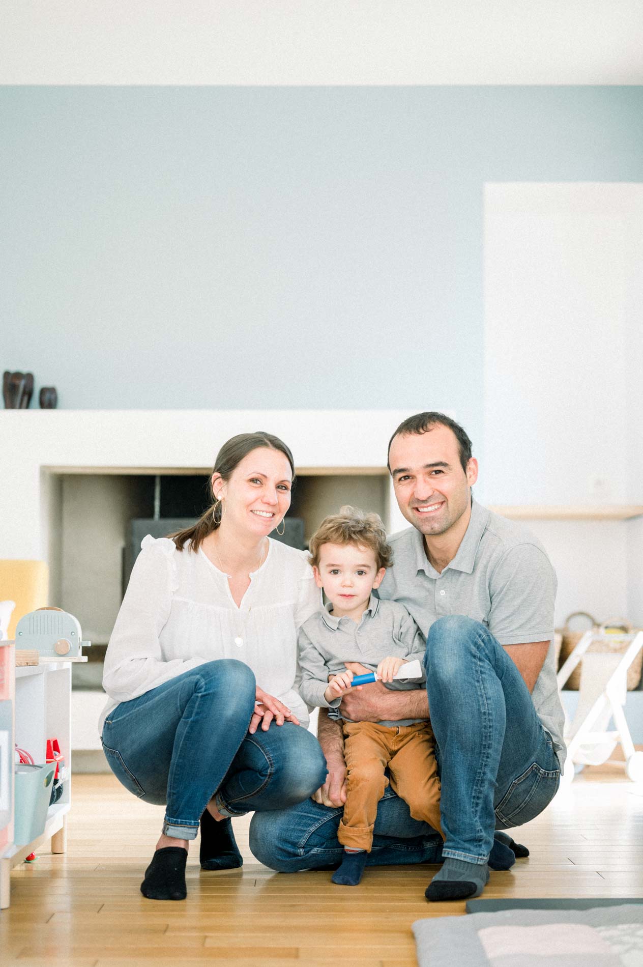 Parents accroupis avec leur petit garçon au milieu du salon