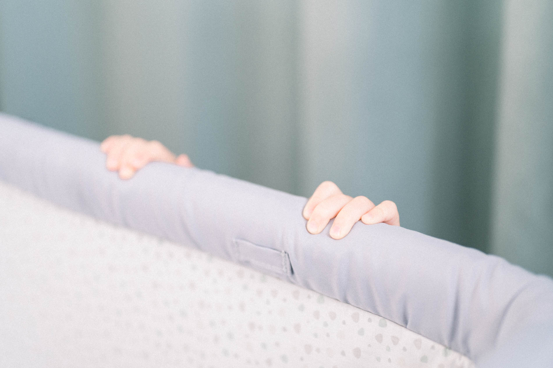 Petites mains de bébé agrippées au bord du berceau