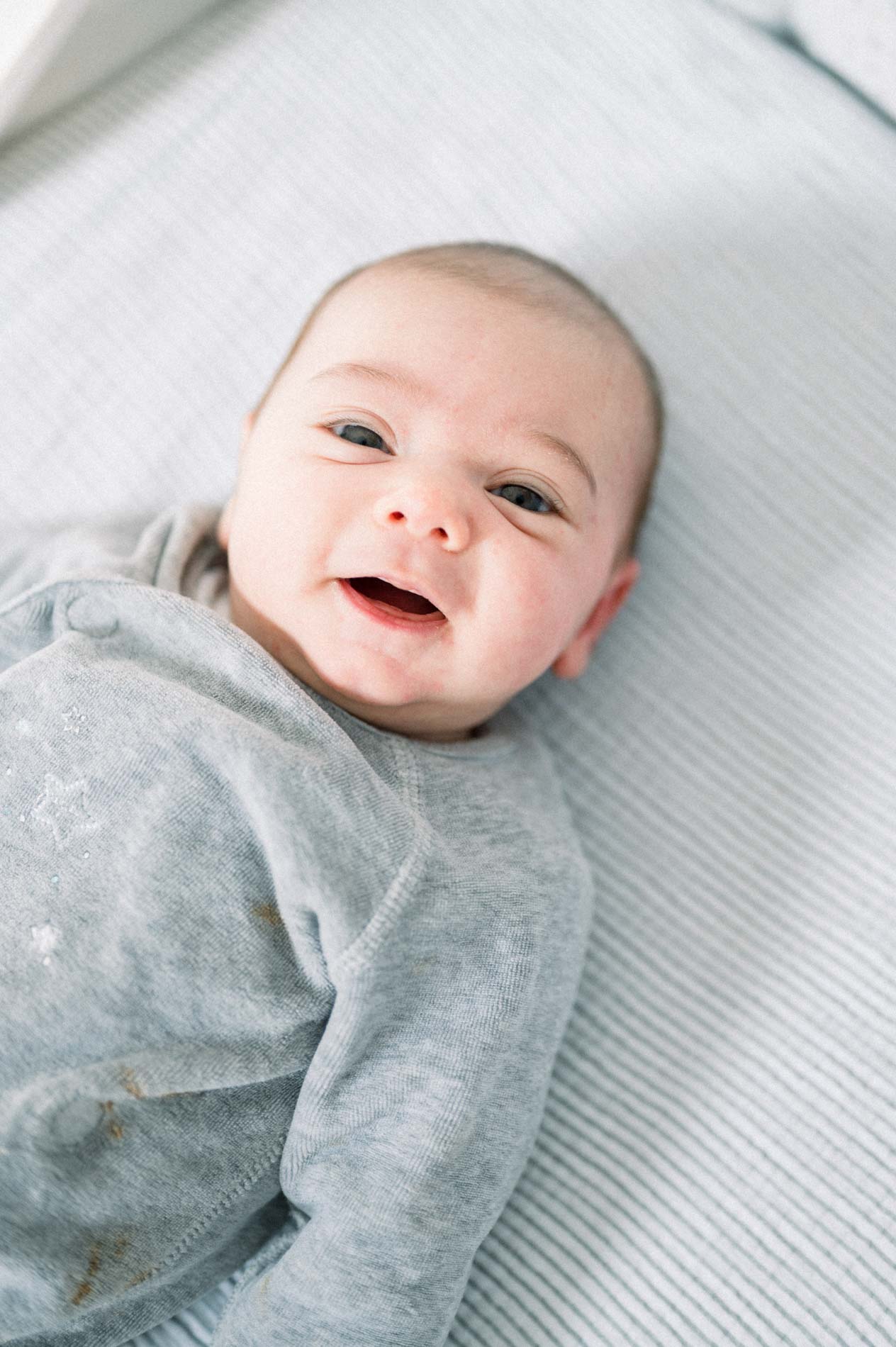Bébé souriant allongé sur le lit en pyjama gris