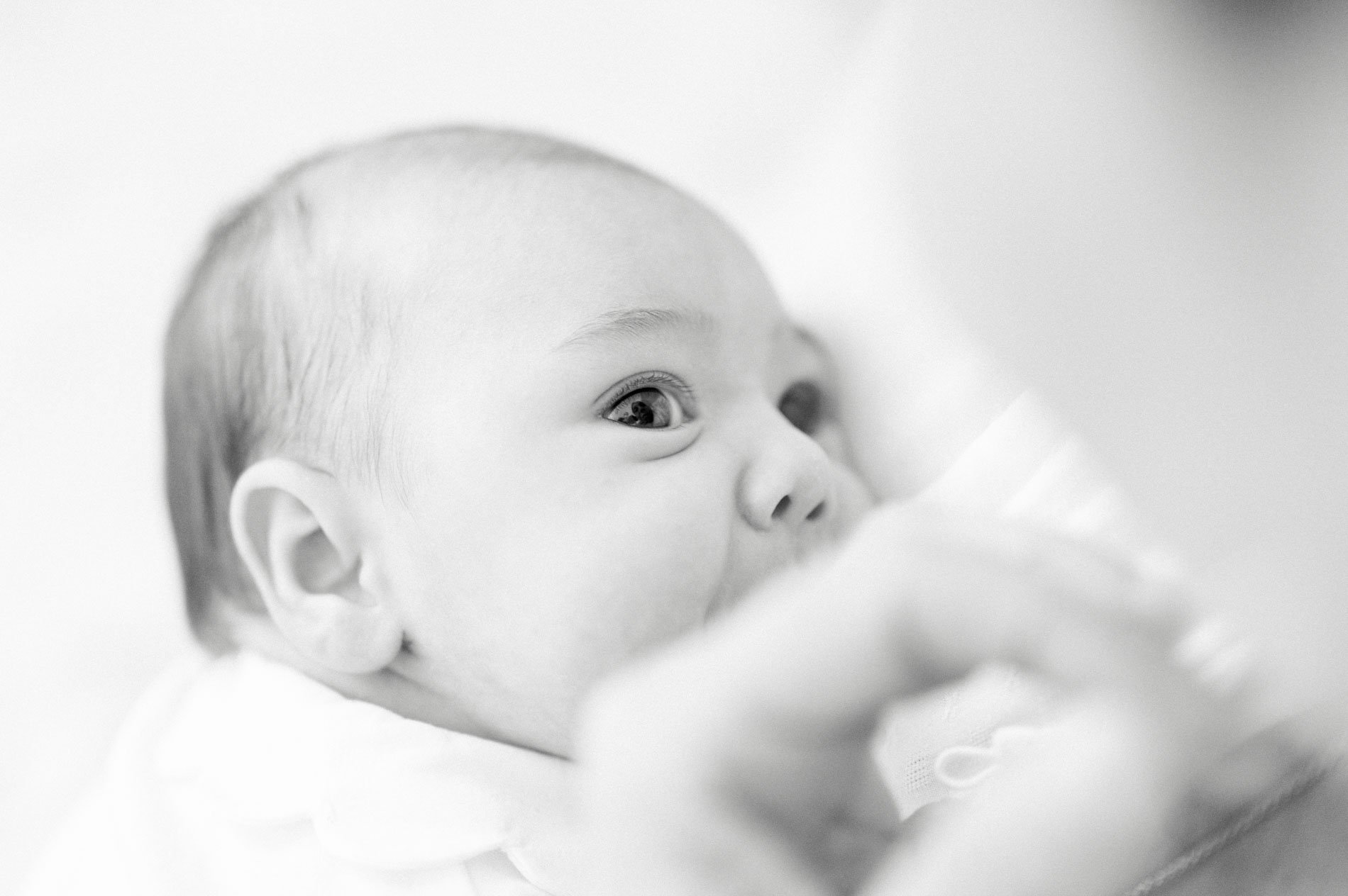 Bébé au regard éveillé dans les bras de ses parents, en noir et blanc