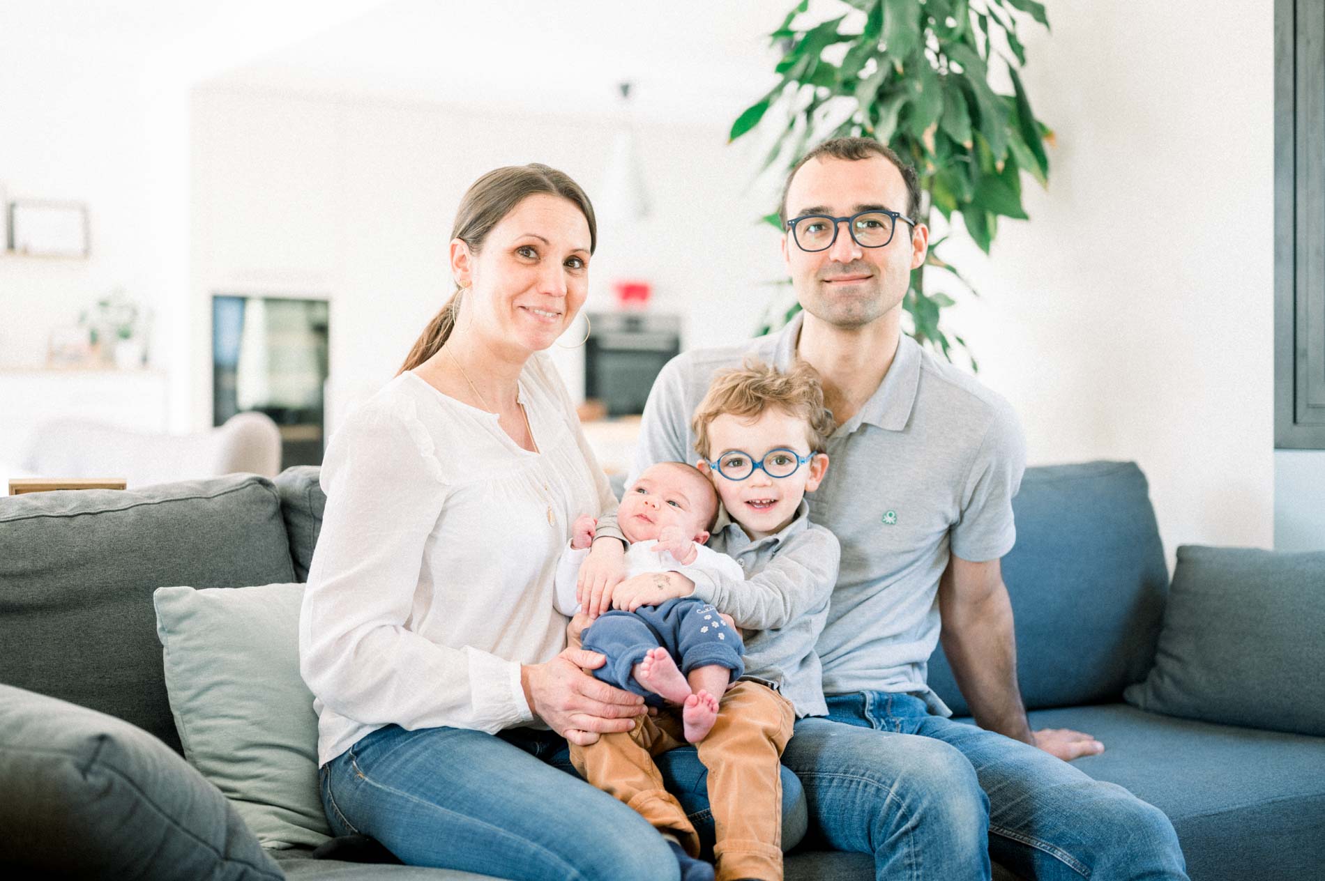 Famille de quatre réunie sur le canapé du salon, bébé dans les bras