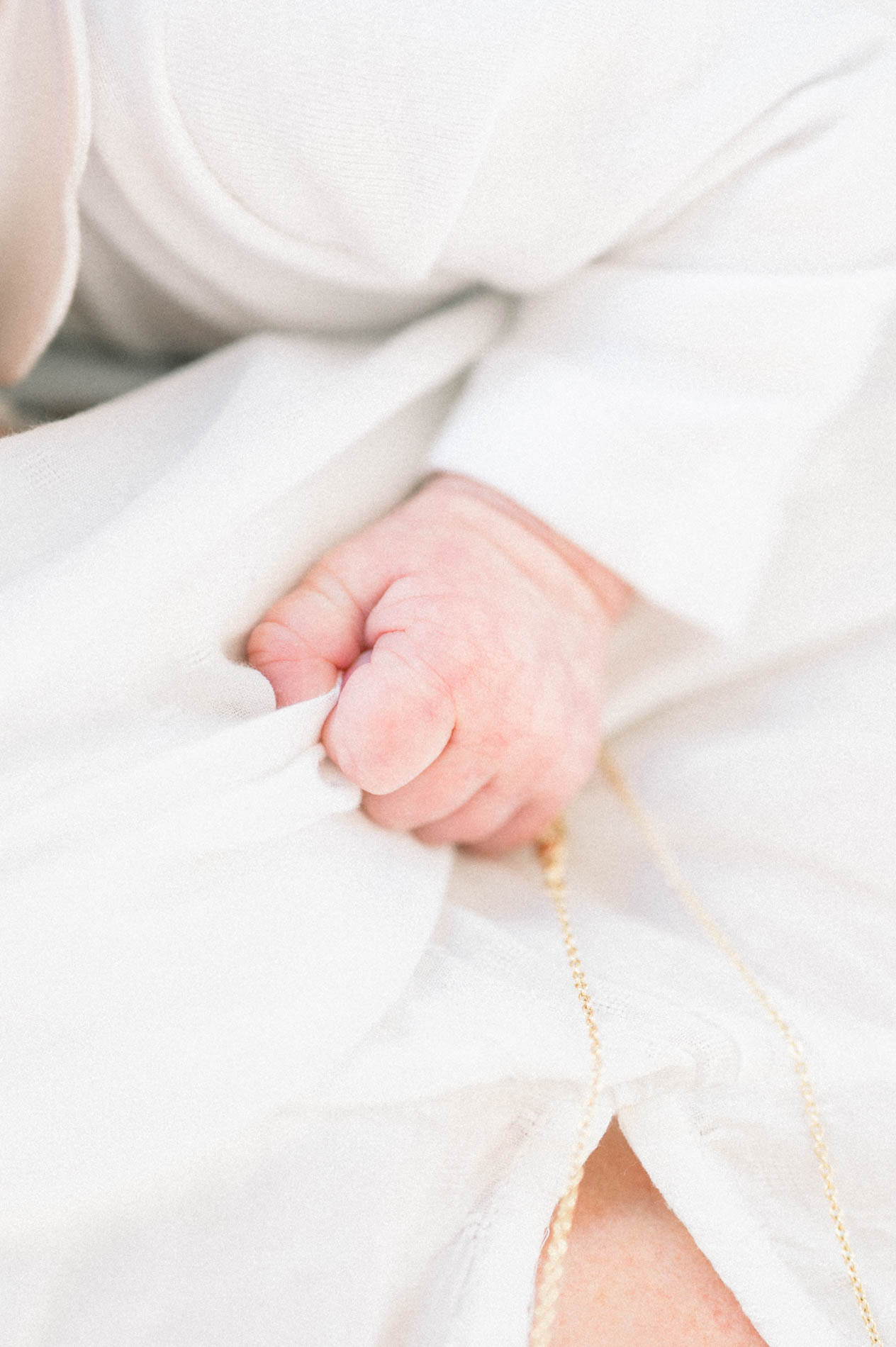 Main de bébé serrant le doigt d'un parent, tons clairs