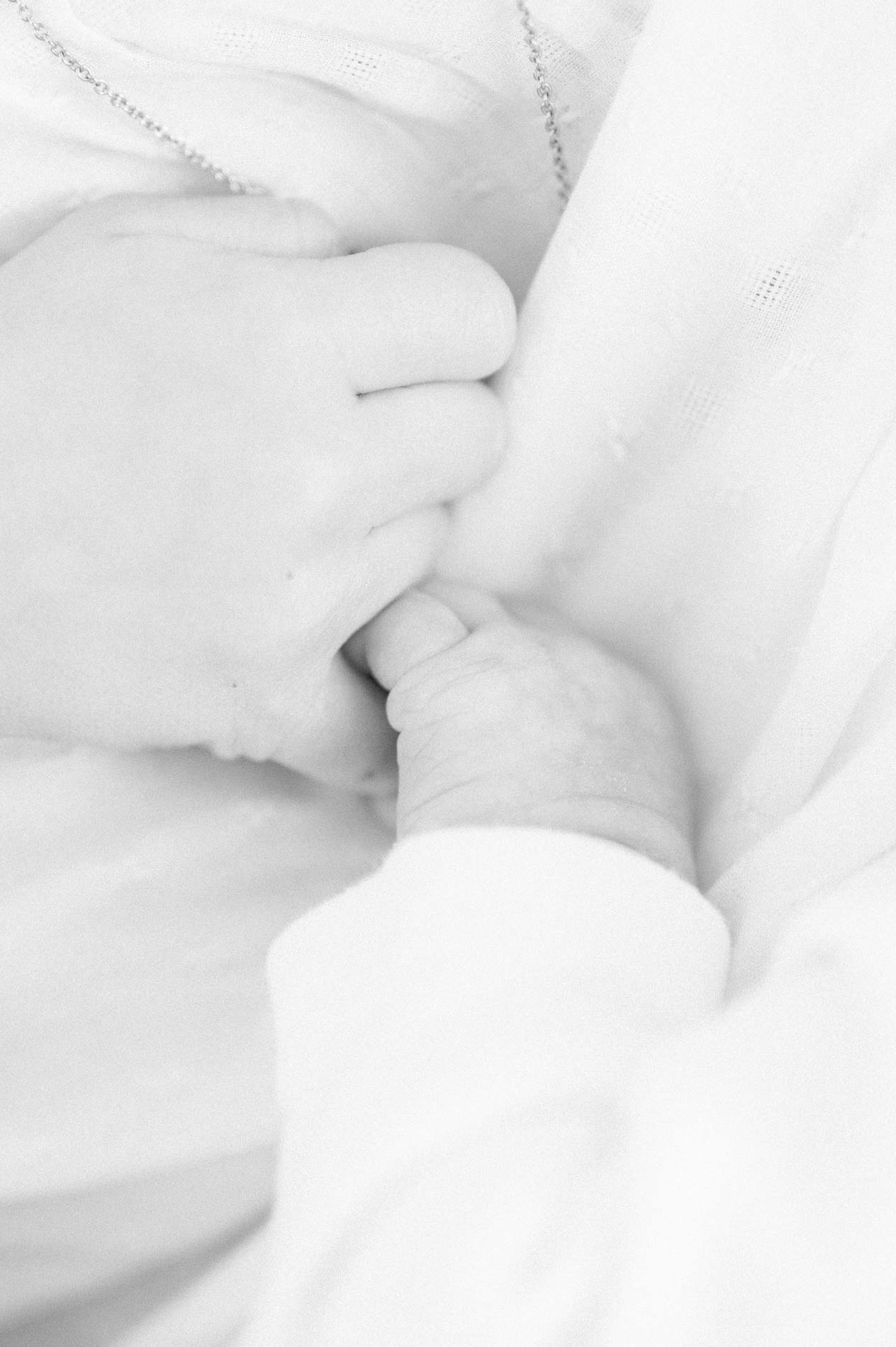 Main de bébé tenant celle de sa maman, en noir et blanc