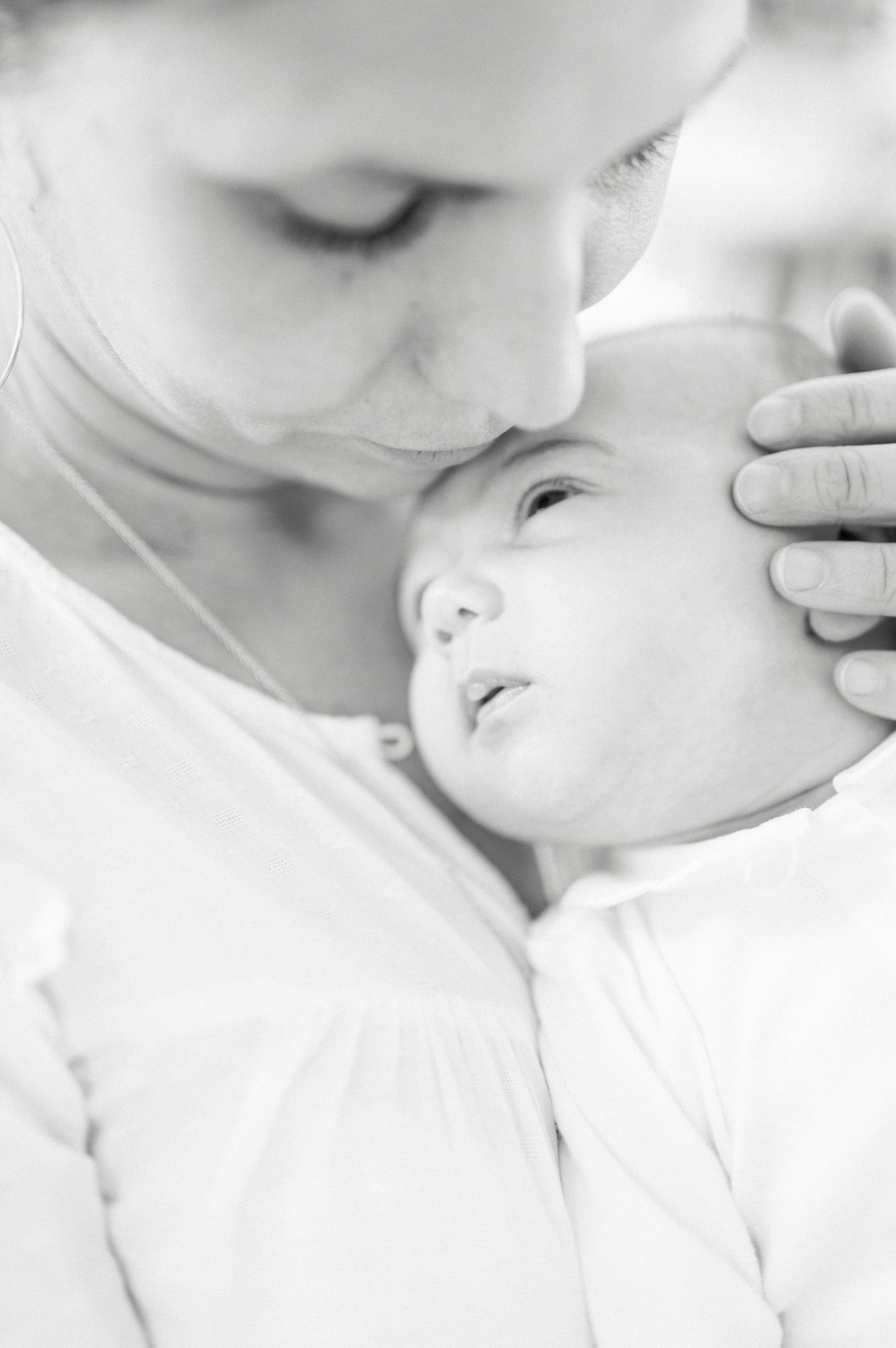Maman embrassant le front de son nouveau-né, en noir et blanc