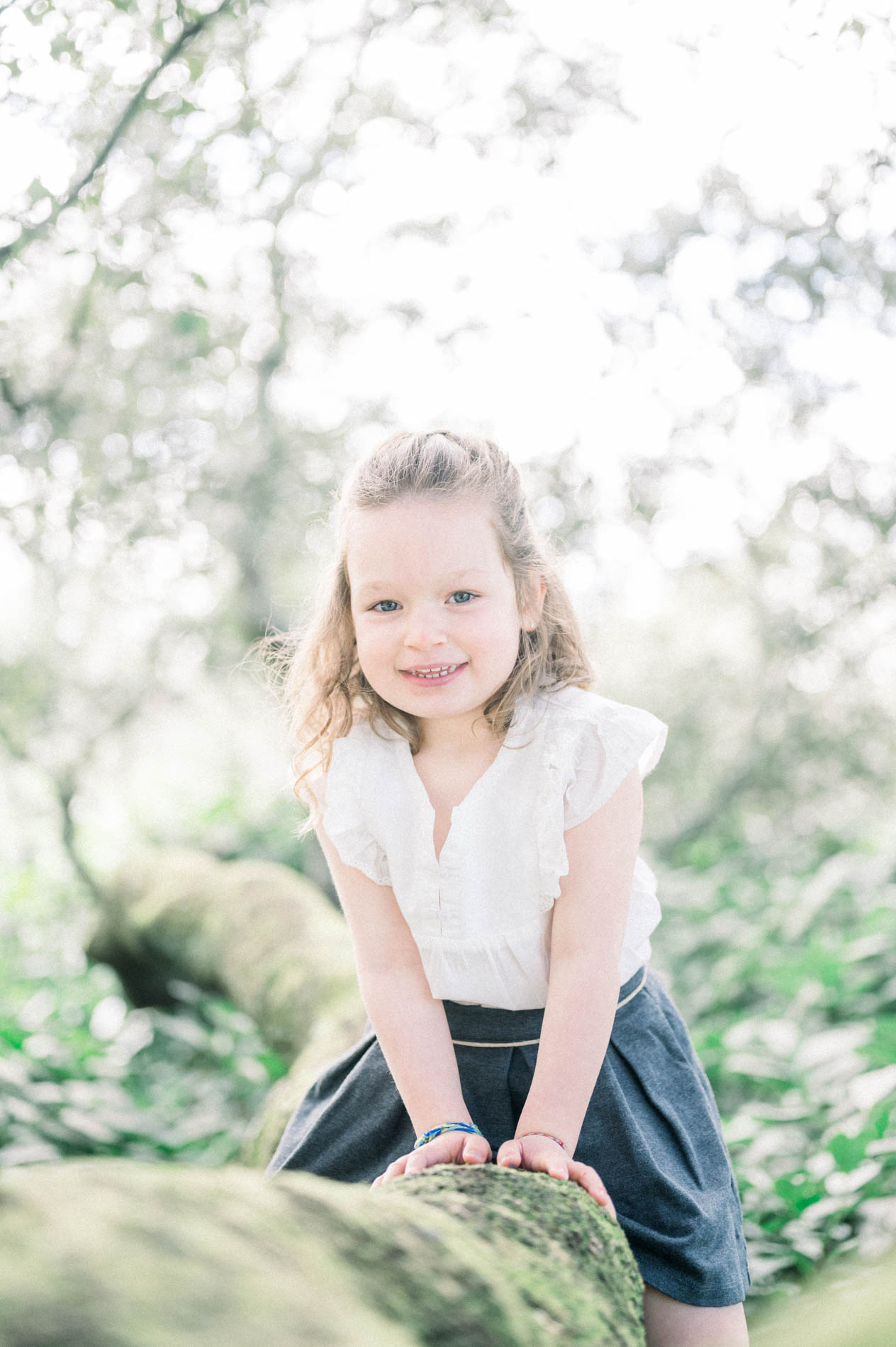 The little girl in a white blouse astride a mossy log at Parc Bordelais