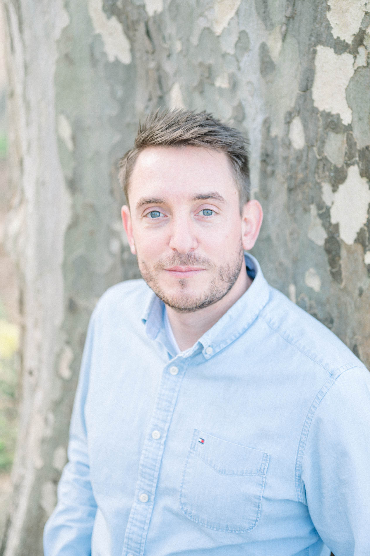 Portrait of the father in a pale blue shirt against plane tree bark