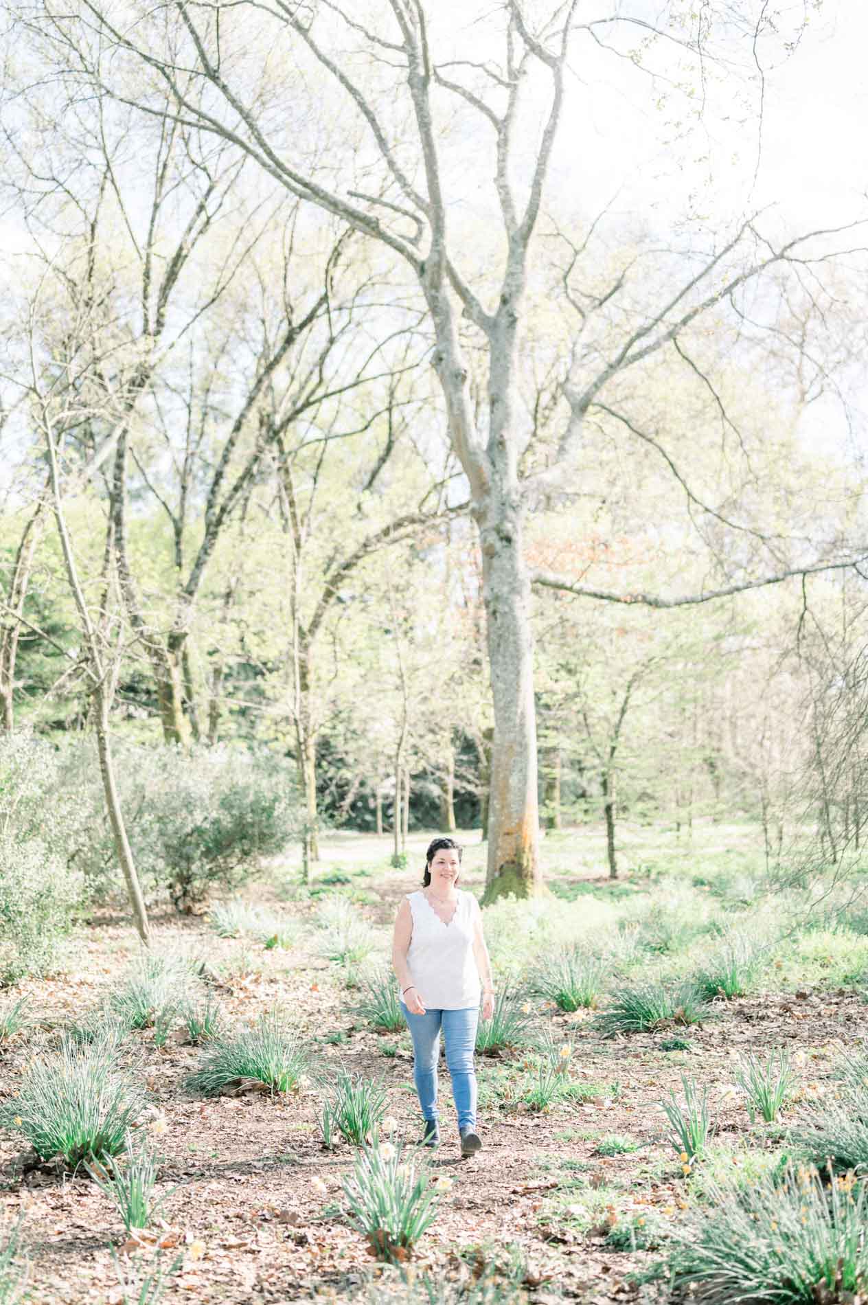 The mother walking alone through the park's spring woodland