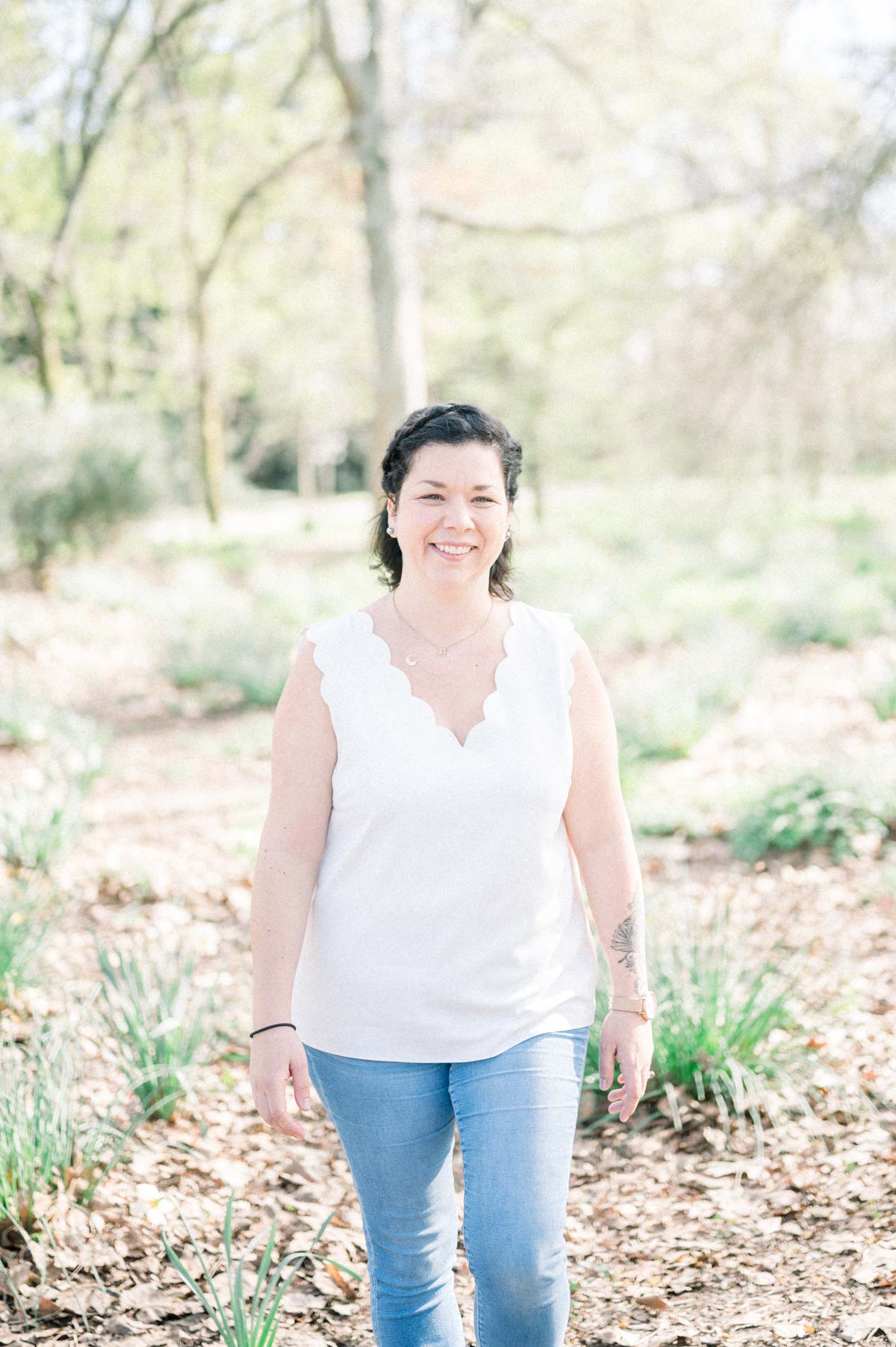 The smiling mother in jeans and a white top among daffodil leaves