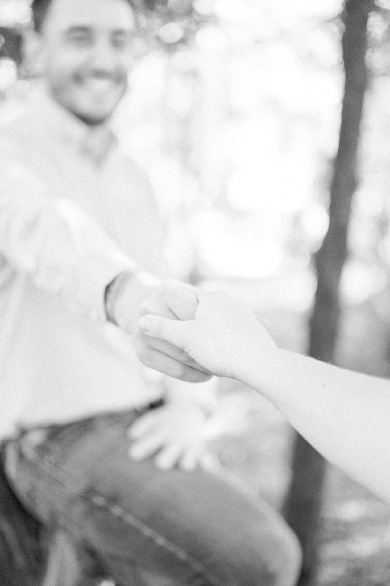 The father reaching for the mother's hand with a smile, in black and white