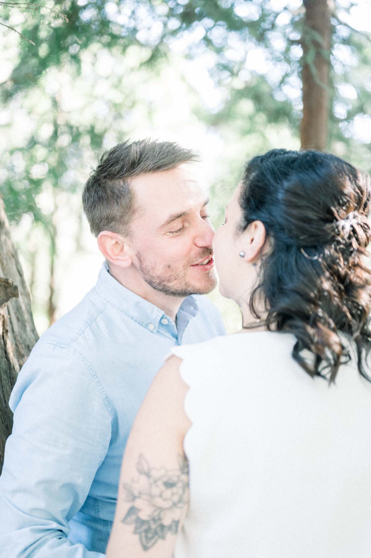 The parents kissing under the trees, the mother's tattooed arm in view