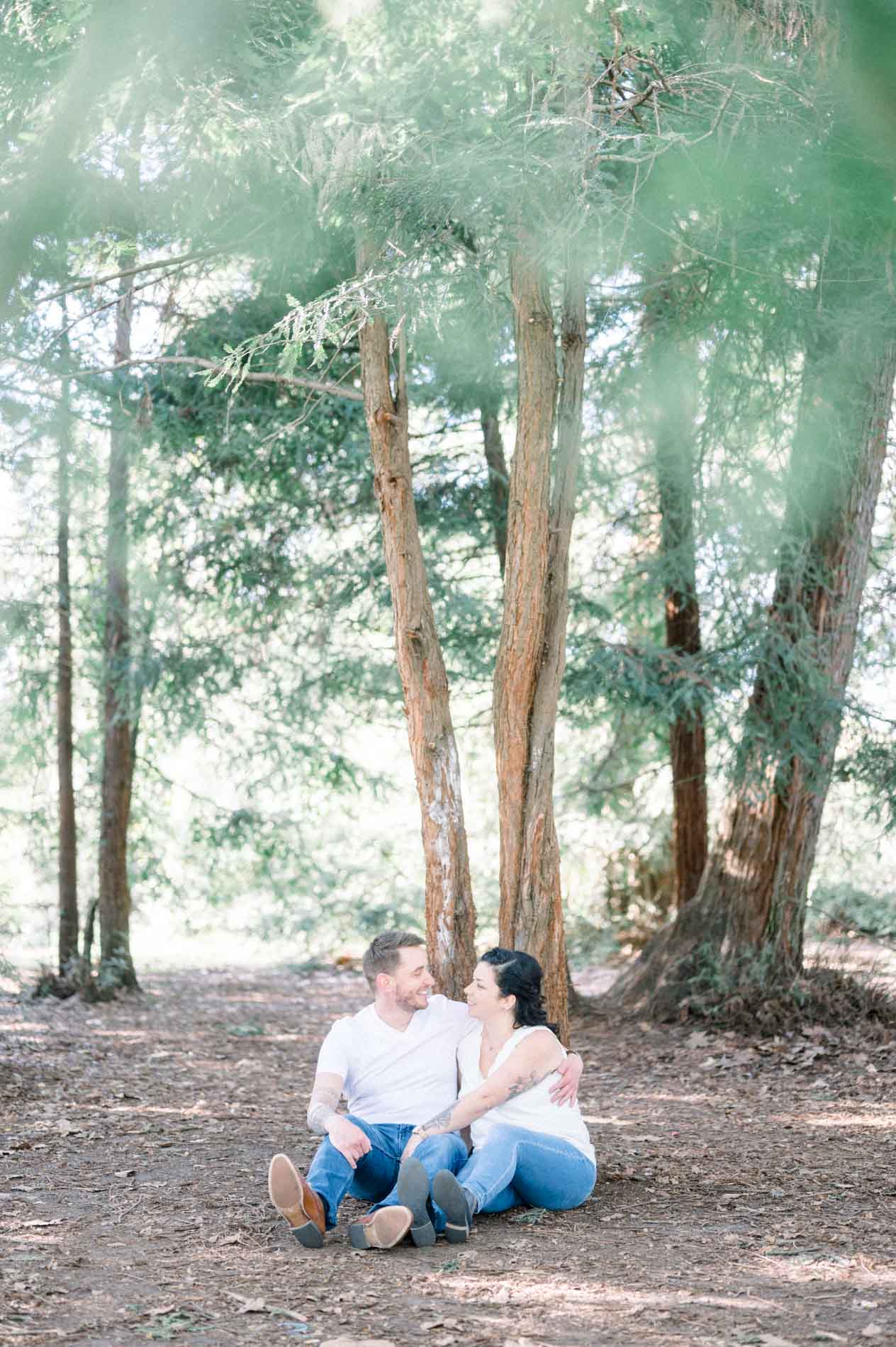 The parents sitting on the ground at the foot of the park's redwoods