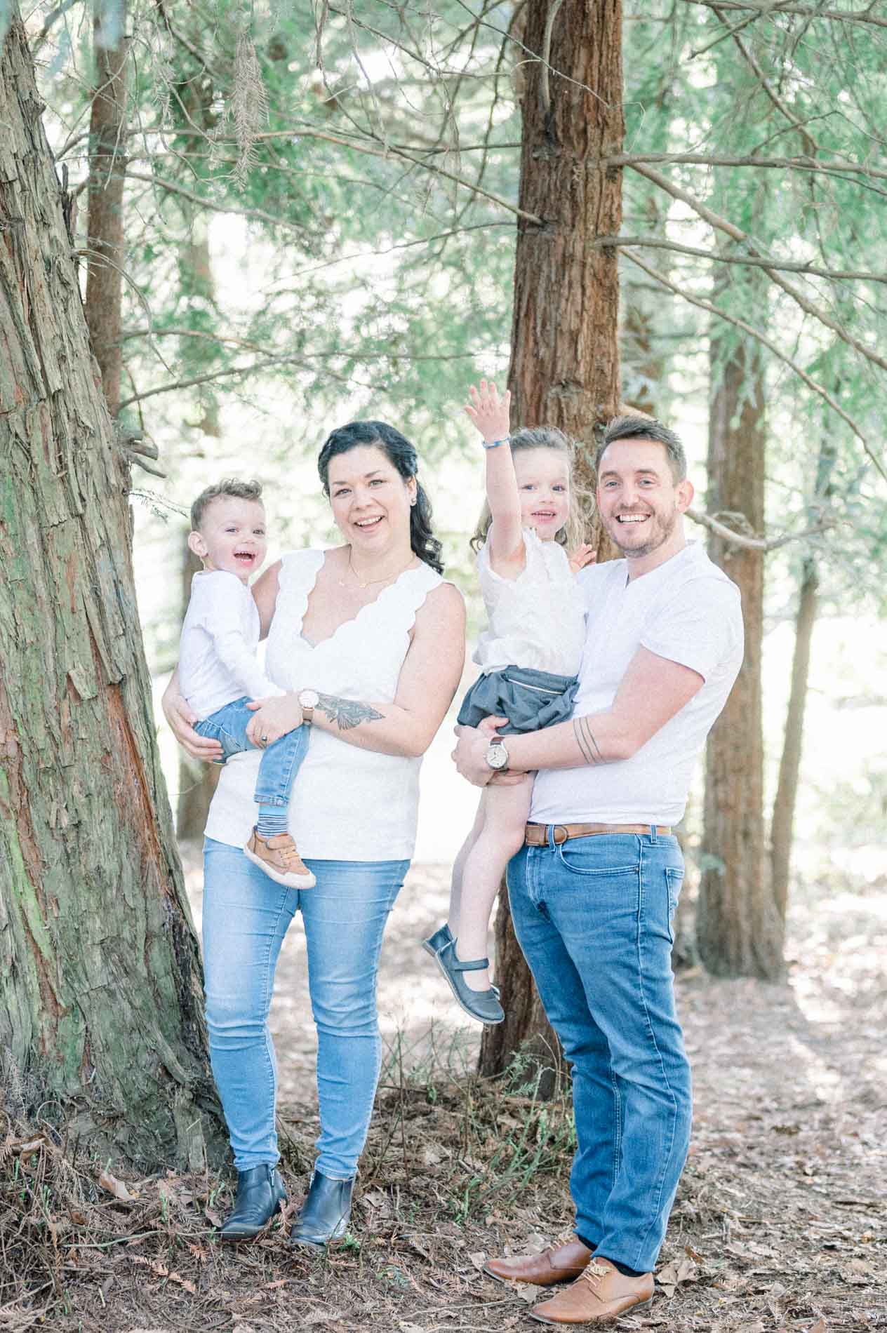 The parents holding their two children in their arms beneath the redwoods