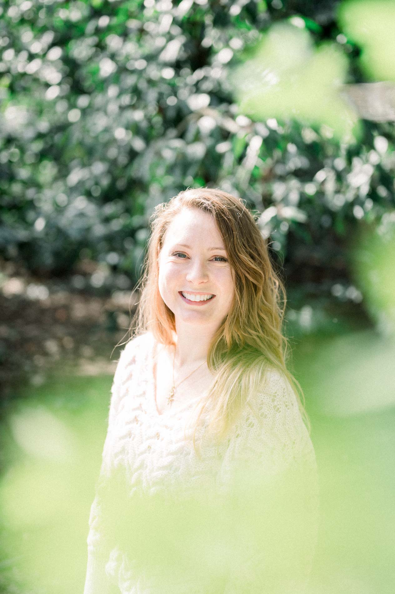 Bright portrait of the smiling sister framed by foliage