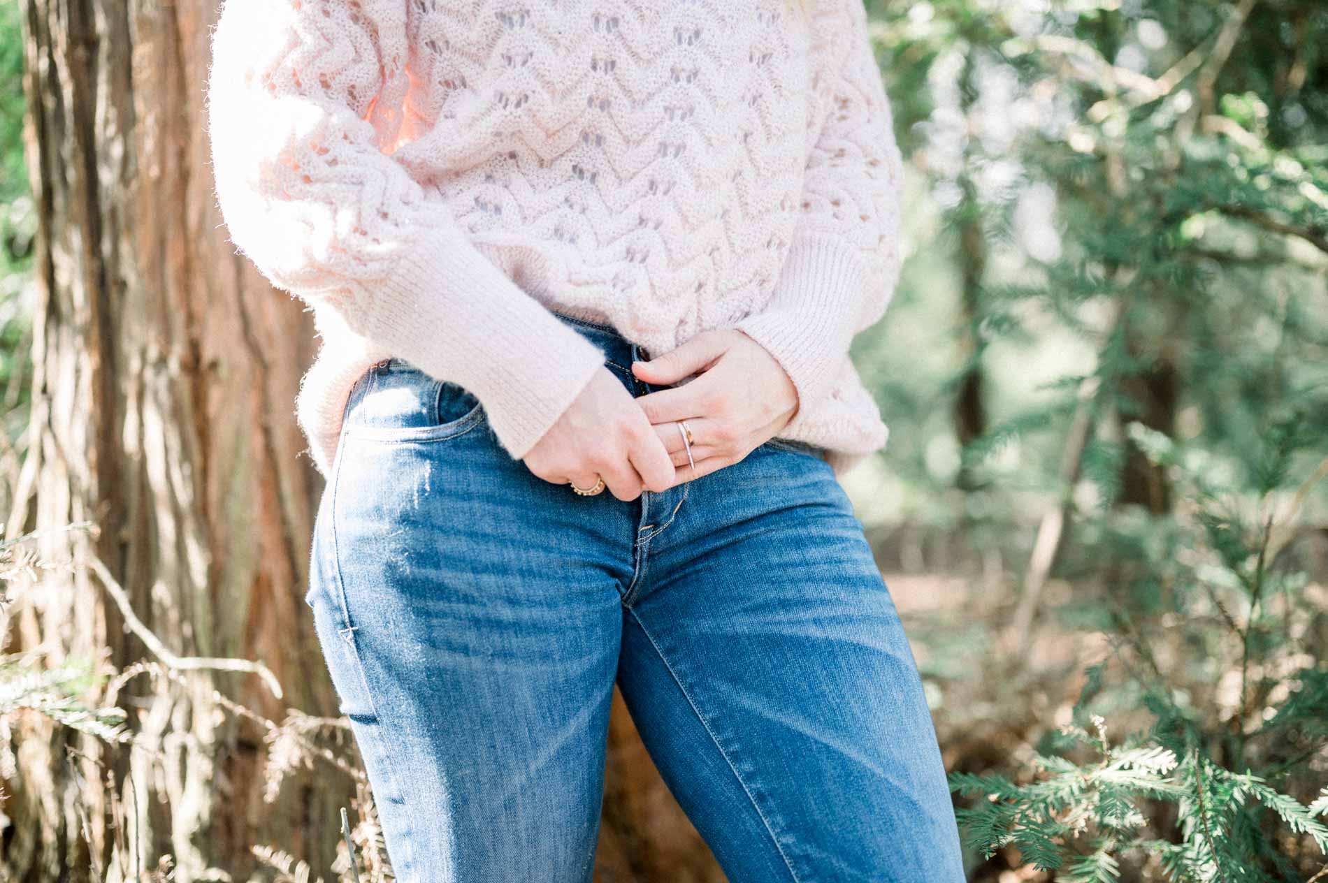 Detail of the sister's hands, pink knit jumper and blue jeans
