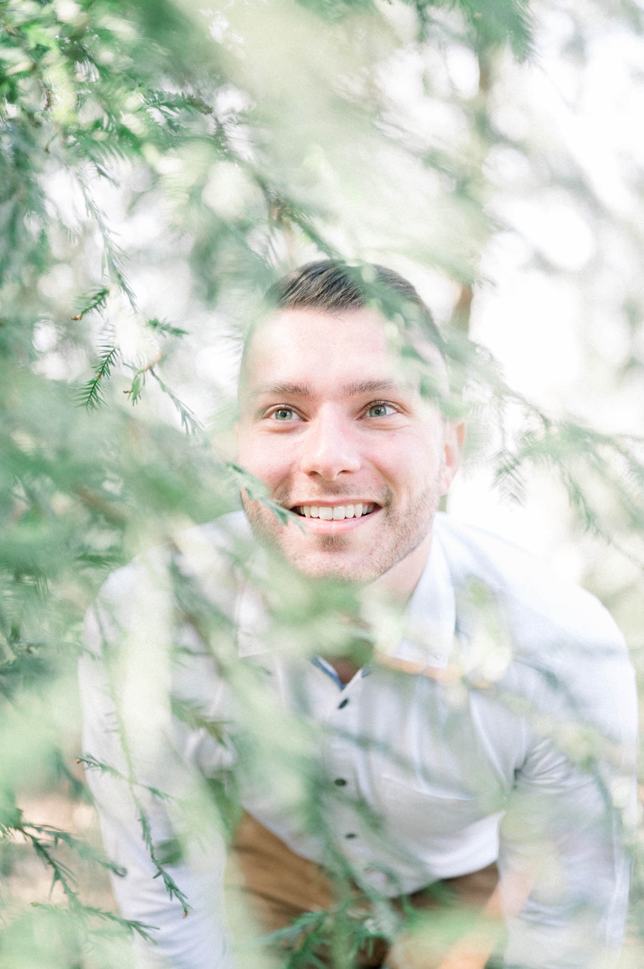Portrait of the brother smiling through soft-focus foliage