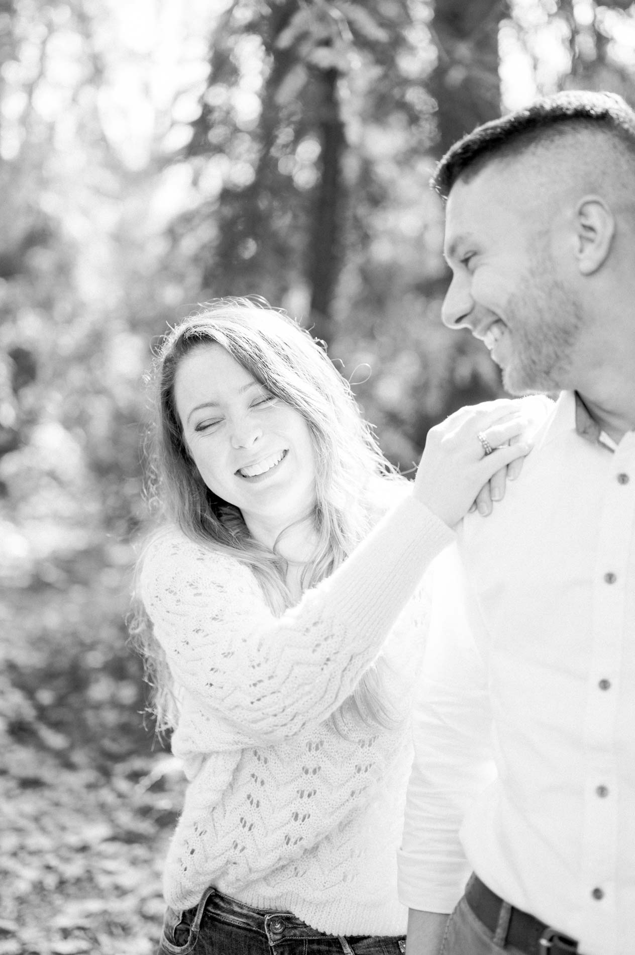 Brother and sister laughing together in the woods, in black and white