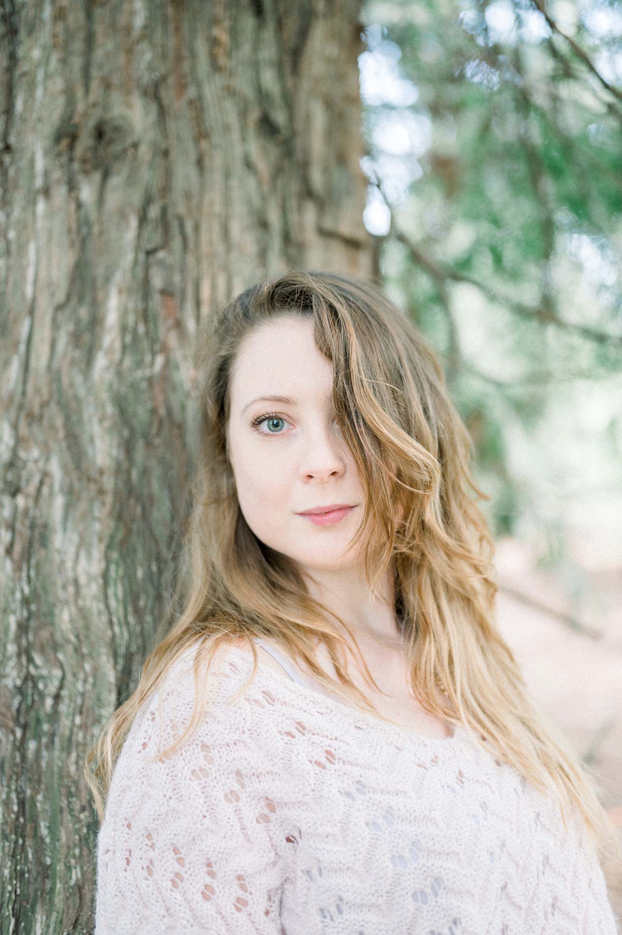 Portrait of the sister with a calm gaze in front of a tree trunk