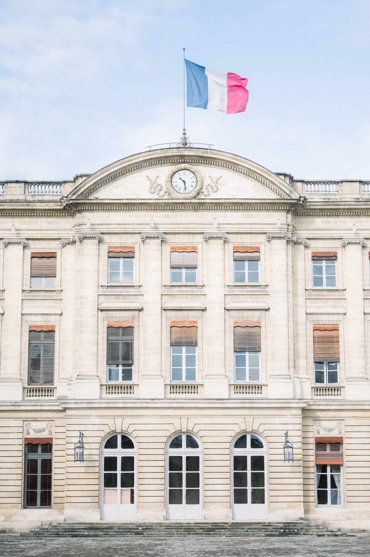 Bordeaux city hall façade with the French flag under a blue sky