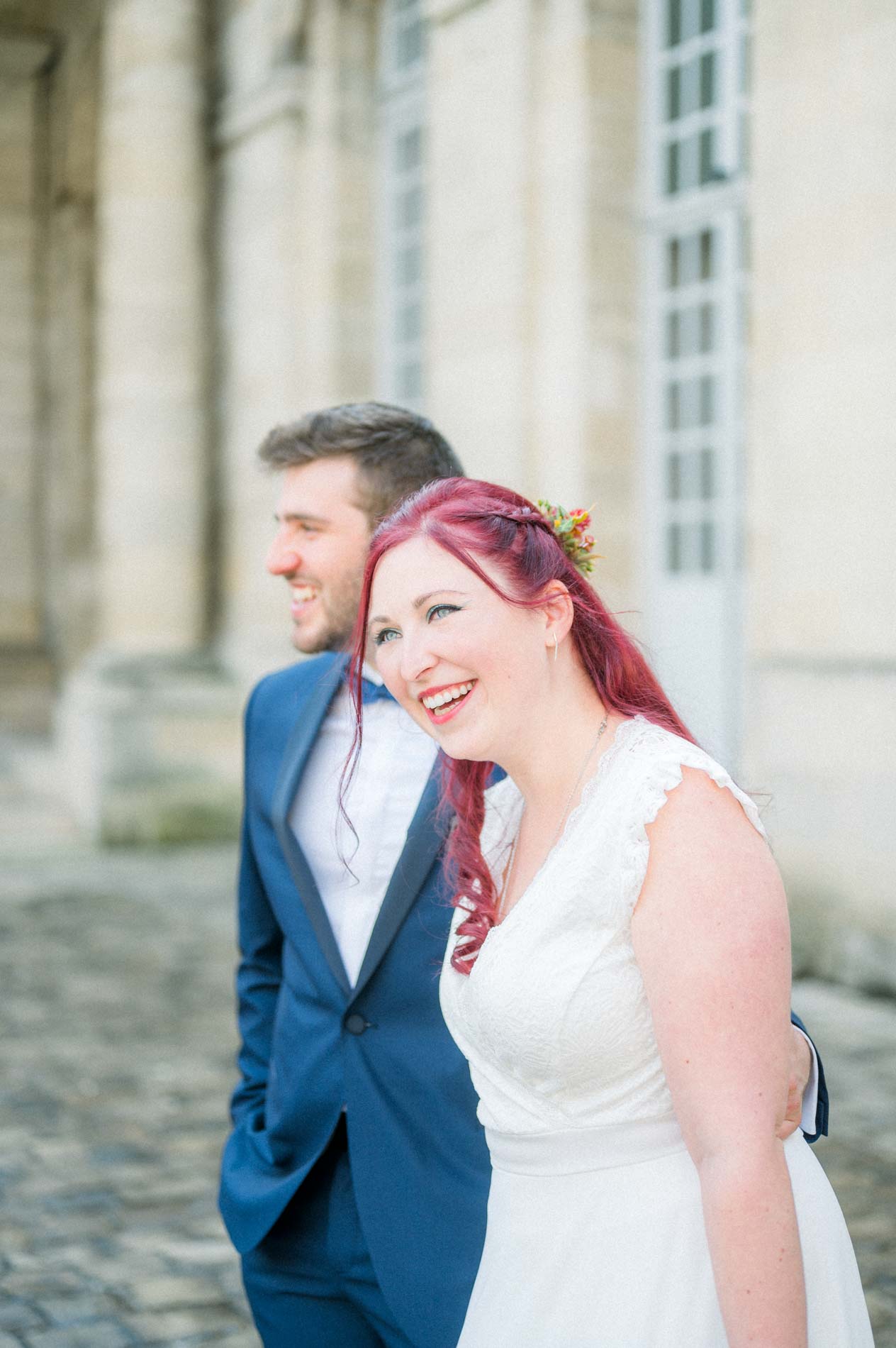 Red-haired bride laughing as she nestles against the groom